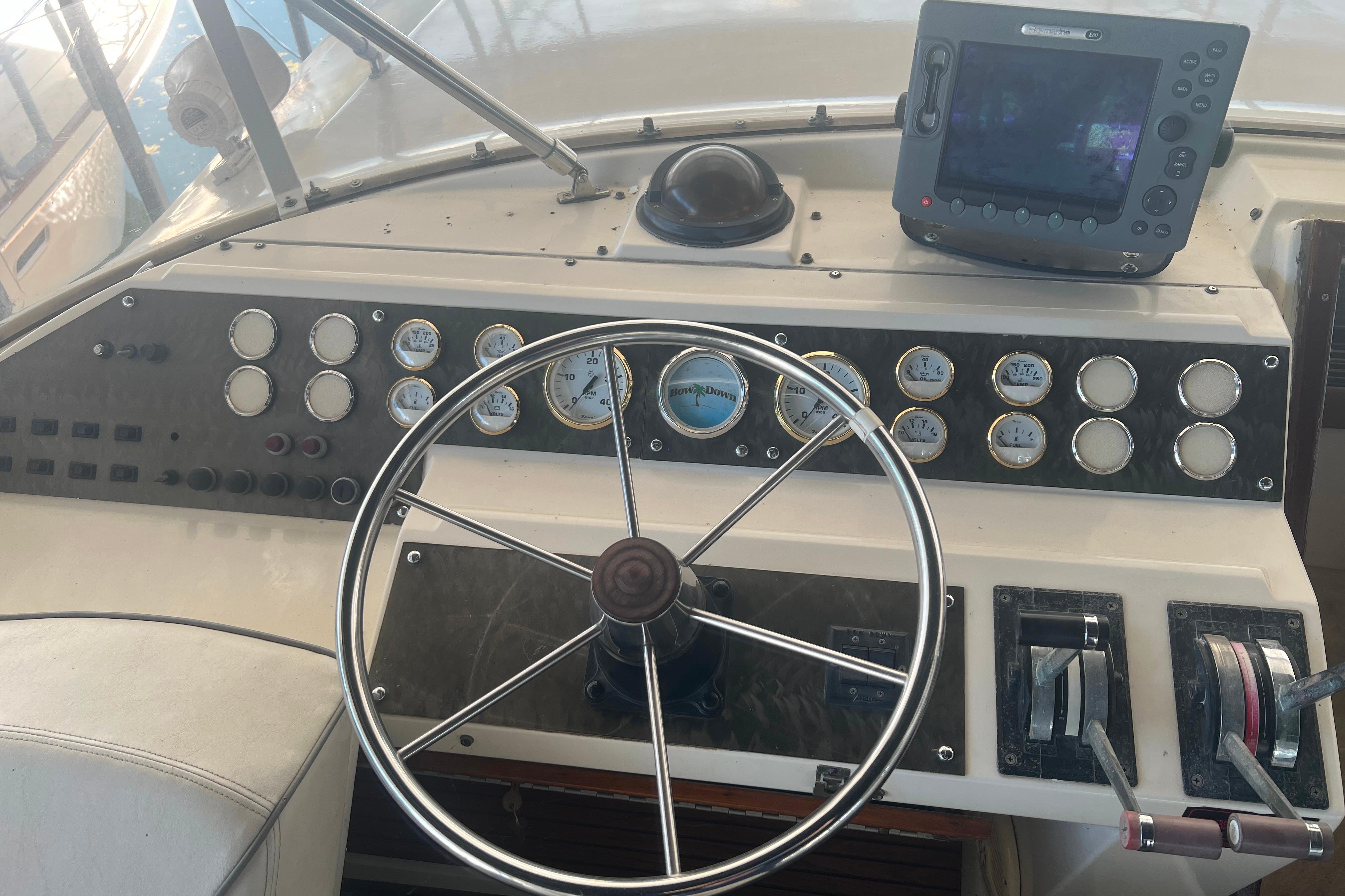 Flybridge helm with steering wheel, gauges, and navigation equipment.
