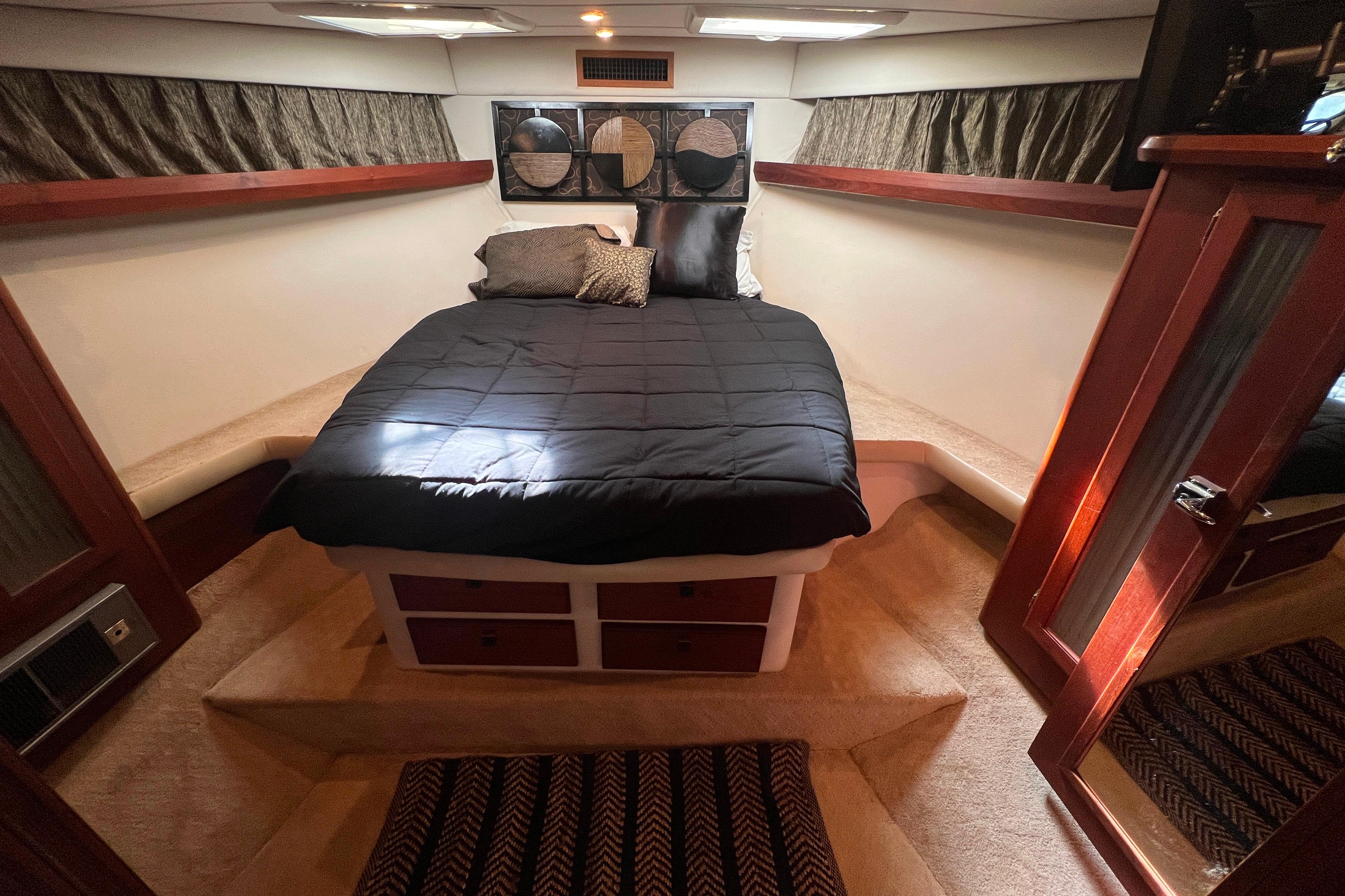 Luxurious cabin interior of 1986 Bayliner 4550 Motoryacht with cozy bed and elegant wood accents.