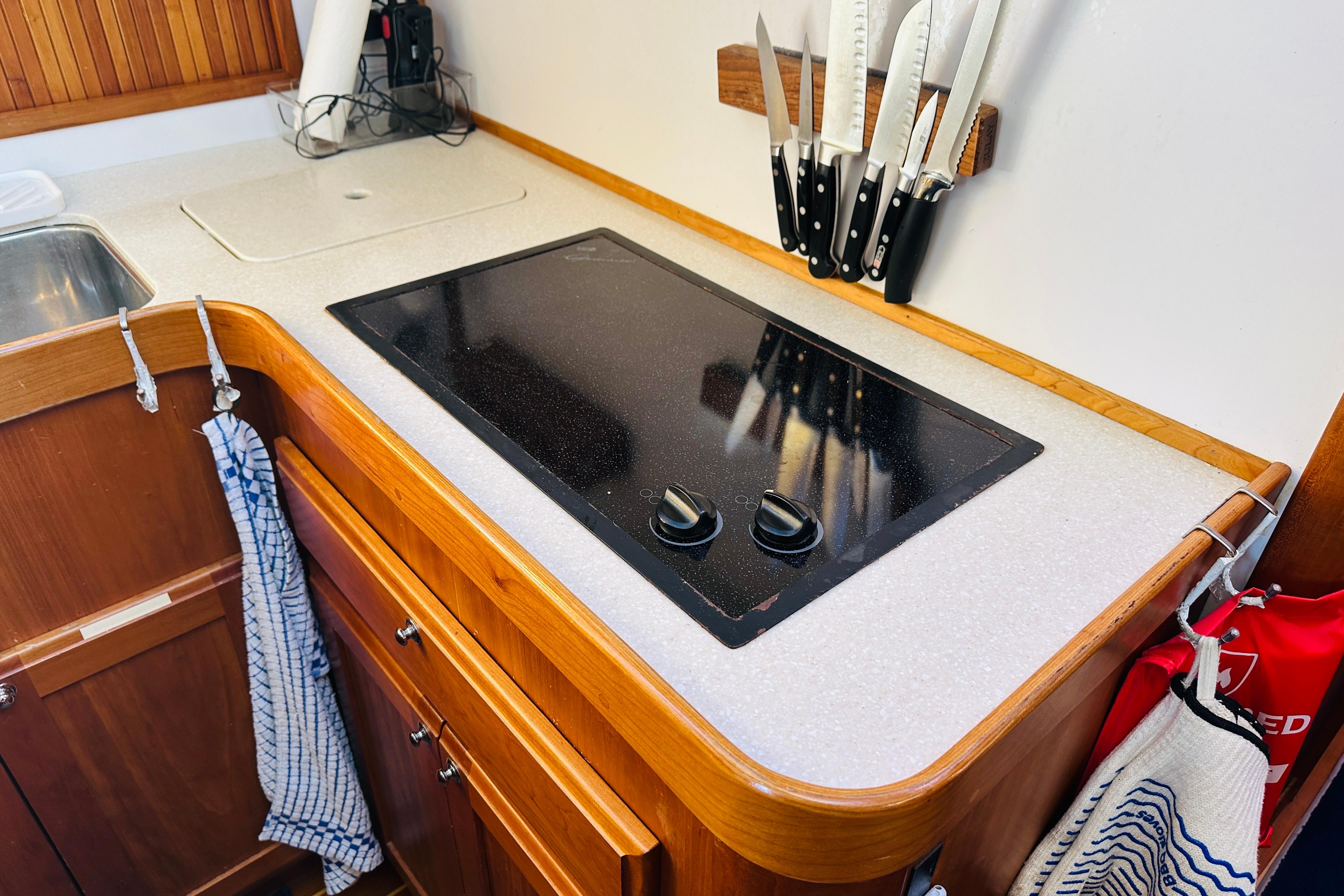 2006 Sabre 42 Fly Bridge kitchen with stove, knives, and wooden cabinetry.