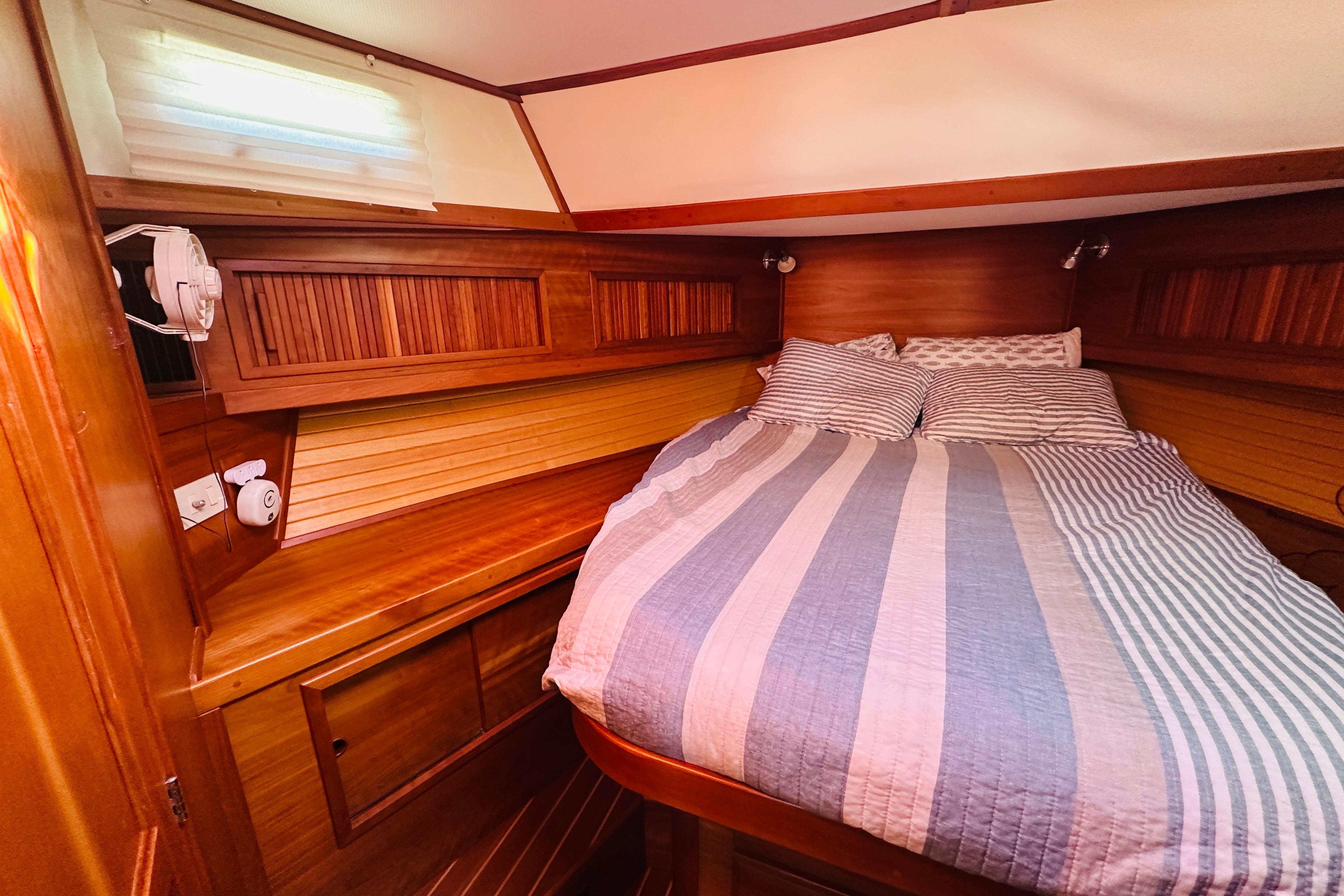 Cozy cabin interior of 2006 Sabre 42 Fly Bridge with striped bedding and wooden accents.