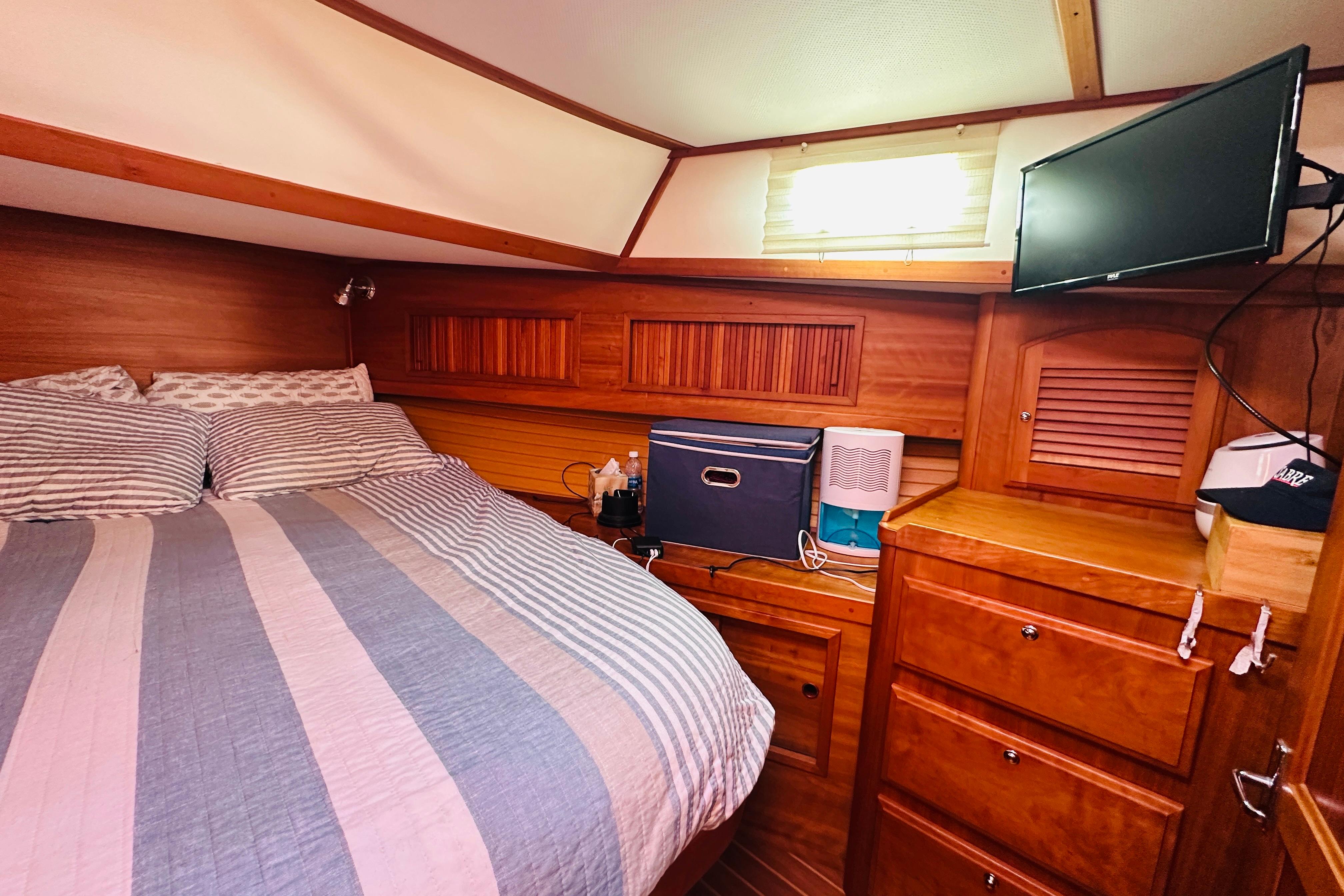 Cozy cabin interior of 2006 Sabre 42 Fly Bridge with bed, TV, and wooden storage.