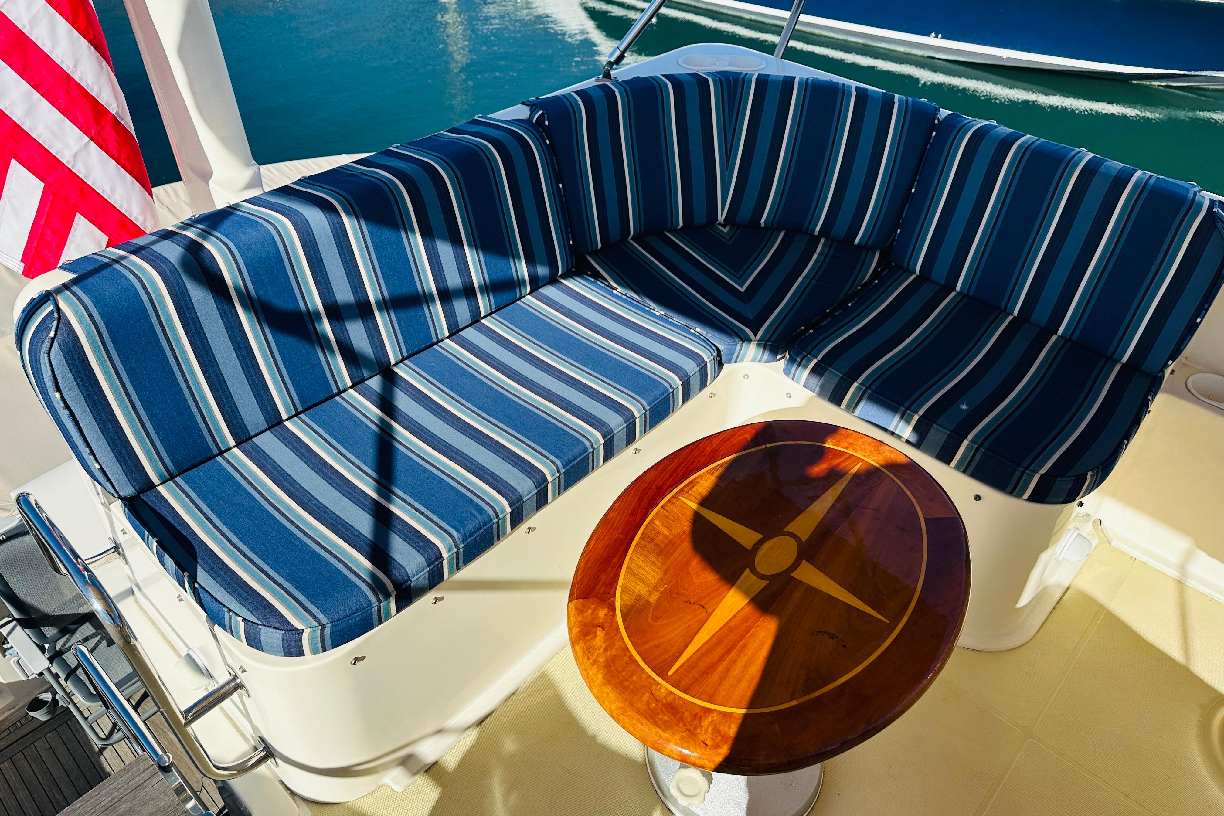 Blue striped seating and wooden table on 2006 Sabre 42 Fly Bridge yacht deck.