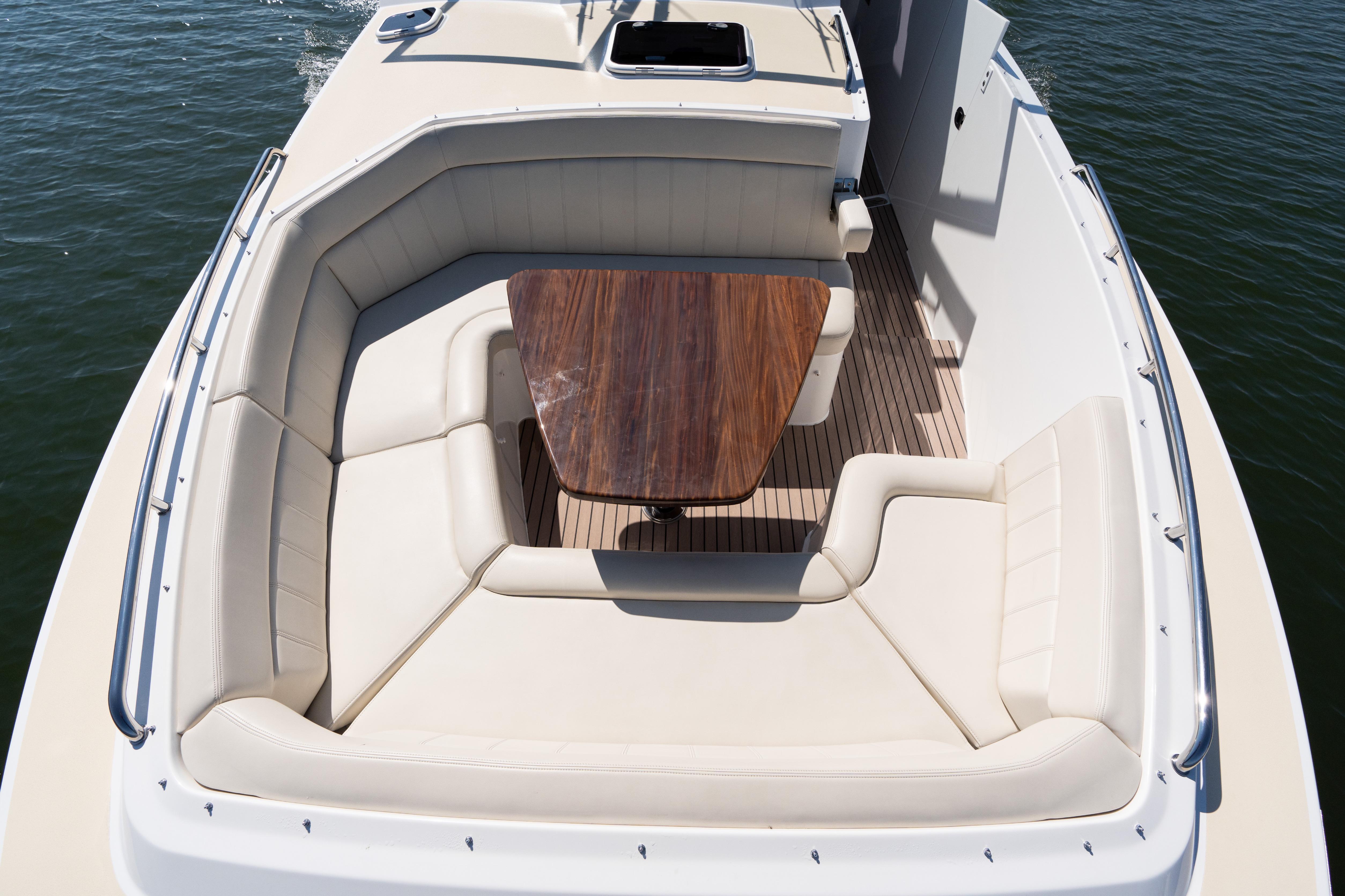 Luxurious seating area on 2023 MJM 4 boat with wooden table and cushioned seats.