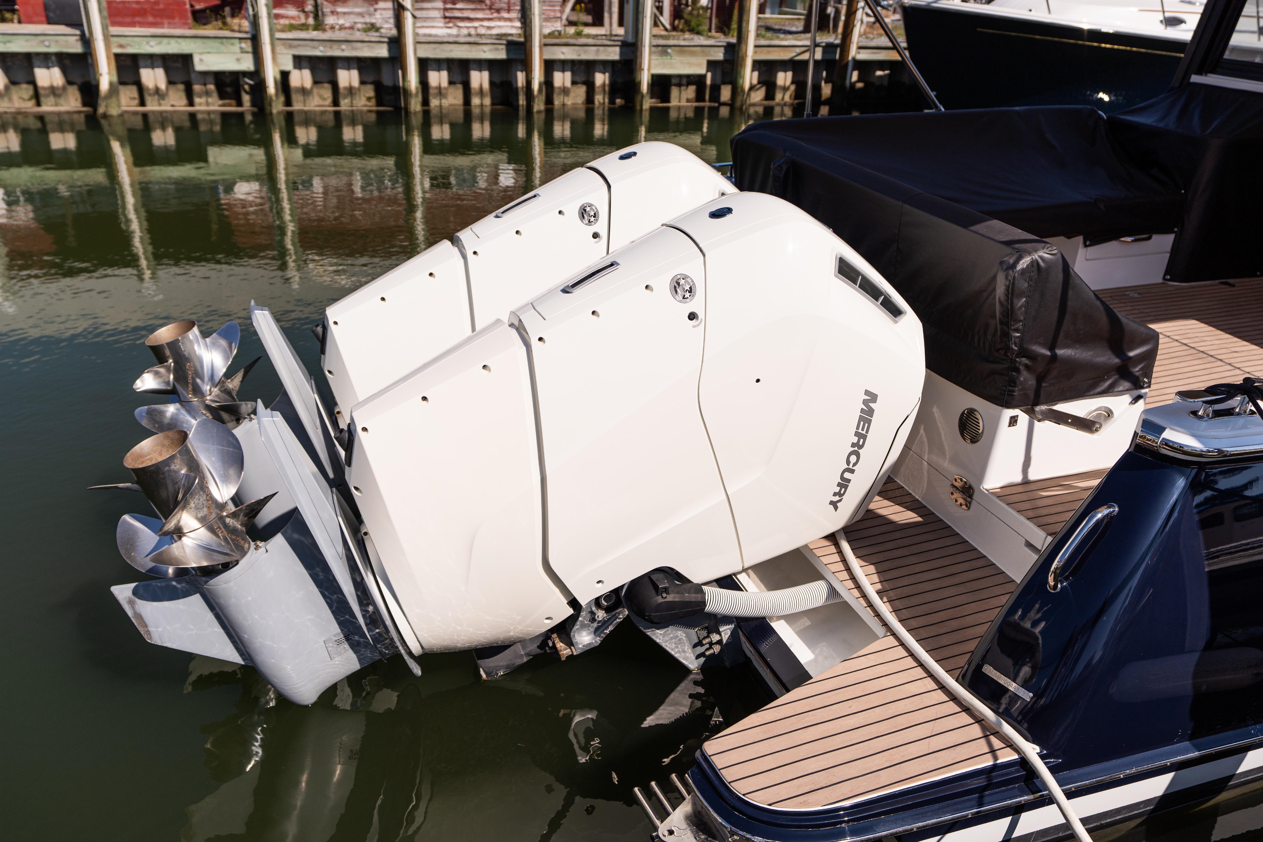 Twin Mercury outboard engines on a 2023 MJM 4 boat, docked by the water.