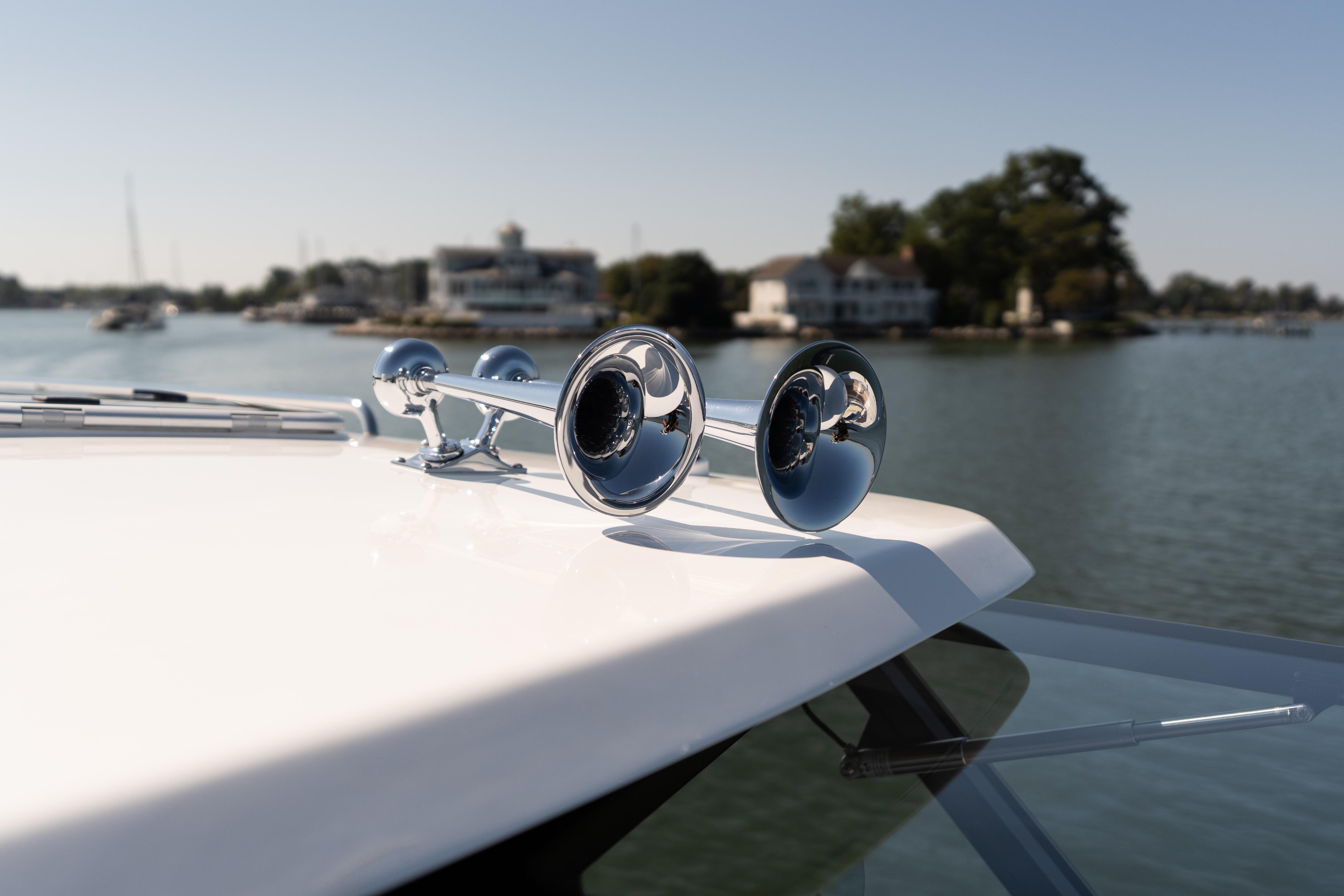 2023 MJM Yachts 4 with chrome horns, docked near waterfront homes.