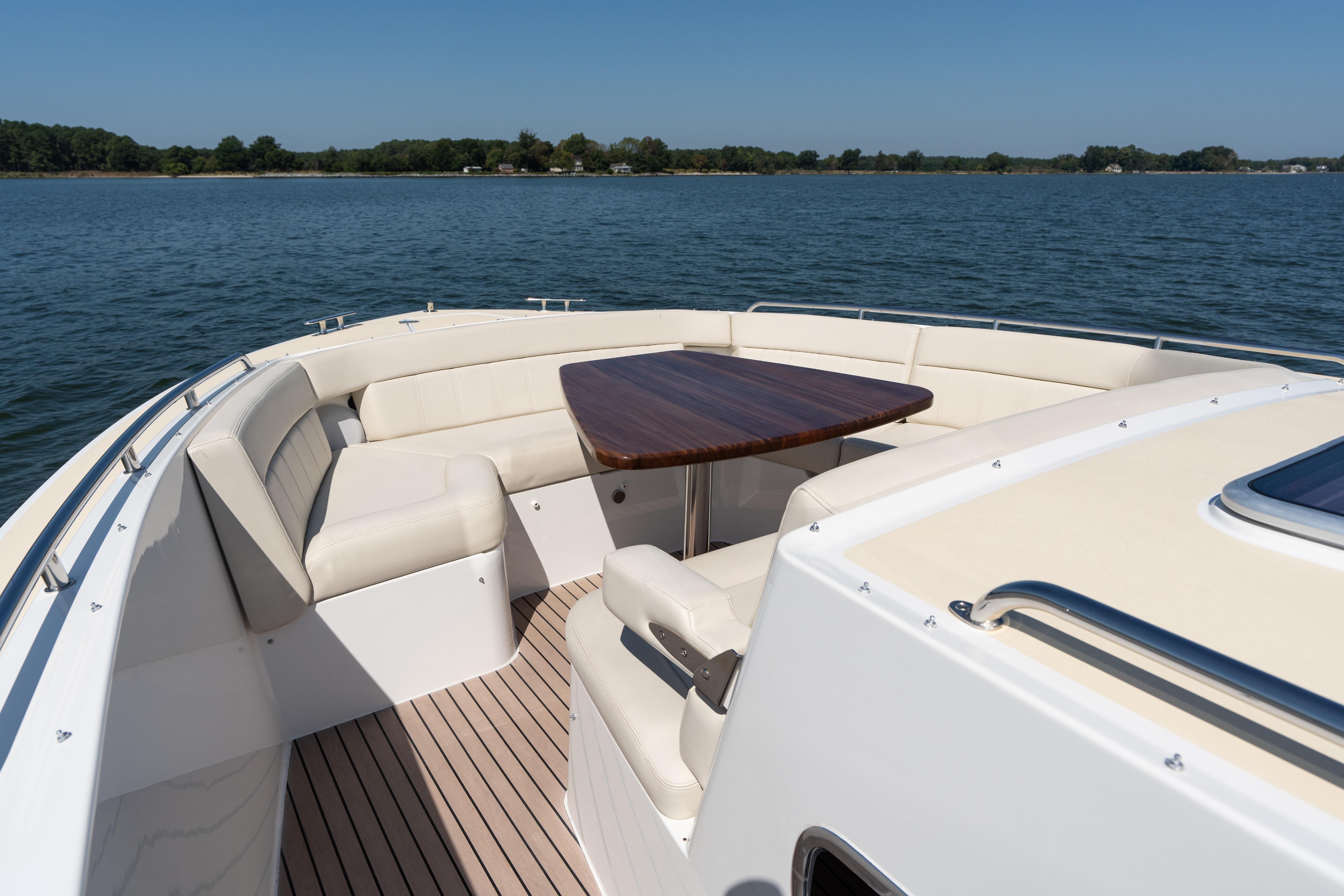 Luxurious seating area on 2023 MJM Yachts 4, featuring elegant wood table and scenic water view.