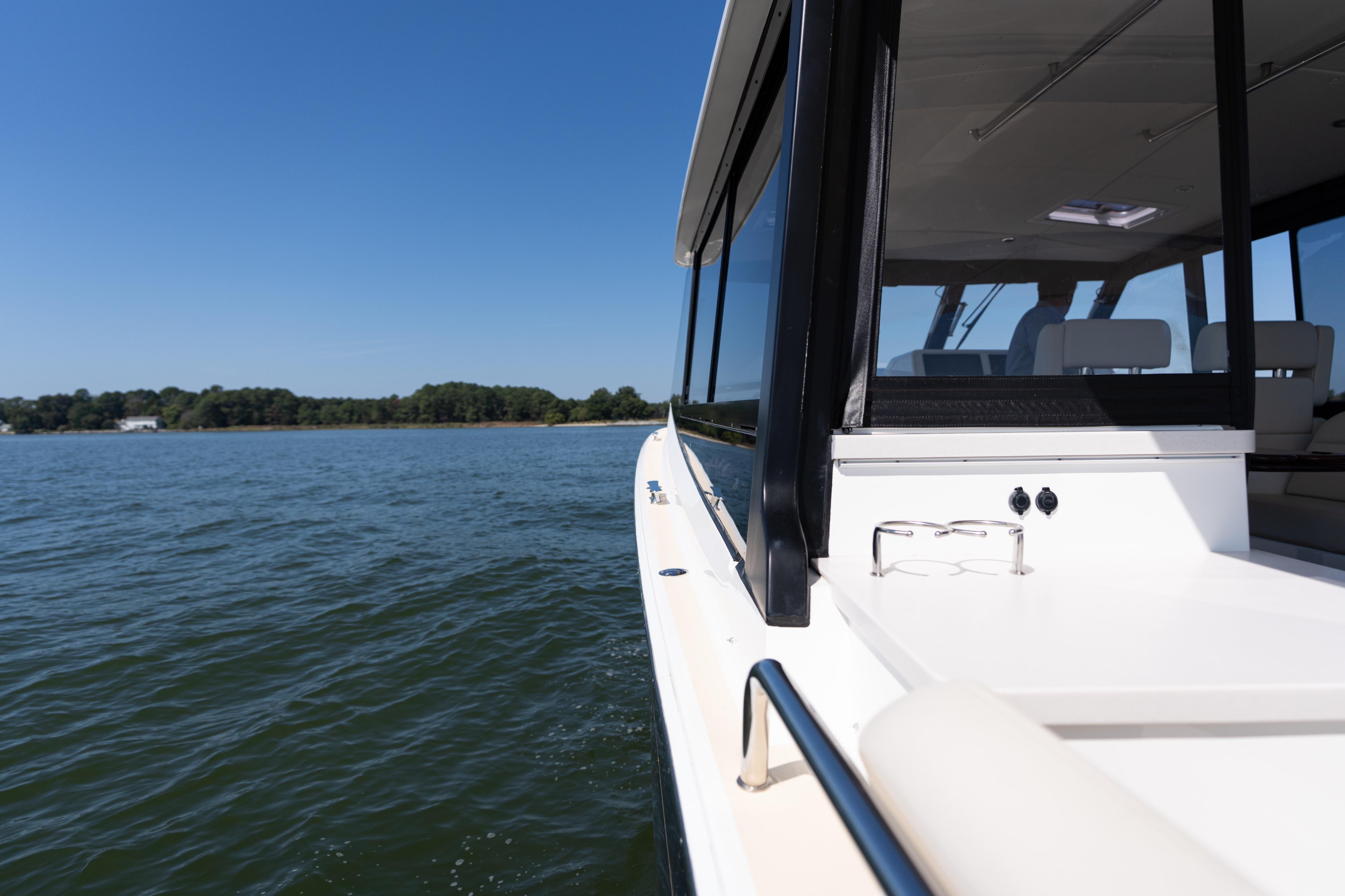 2023 MJM Yachts 4 cruising on a serene lake under a clear blue sky.