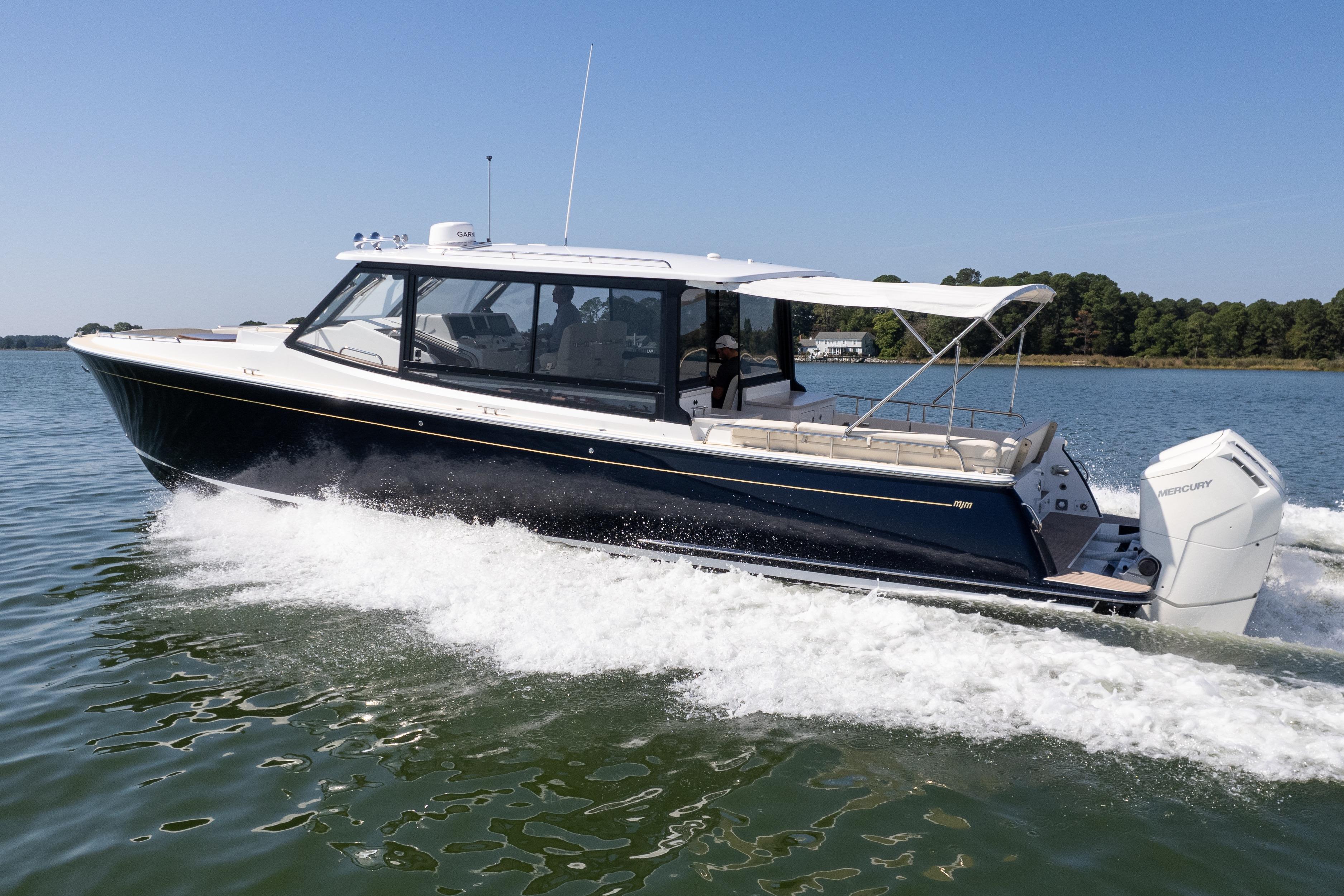 2023 MJM Yachts 4 cruising on a serene lake under clear blue skies.