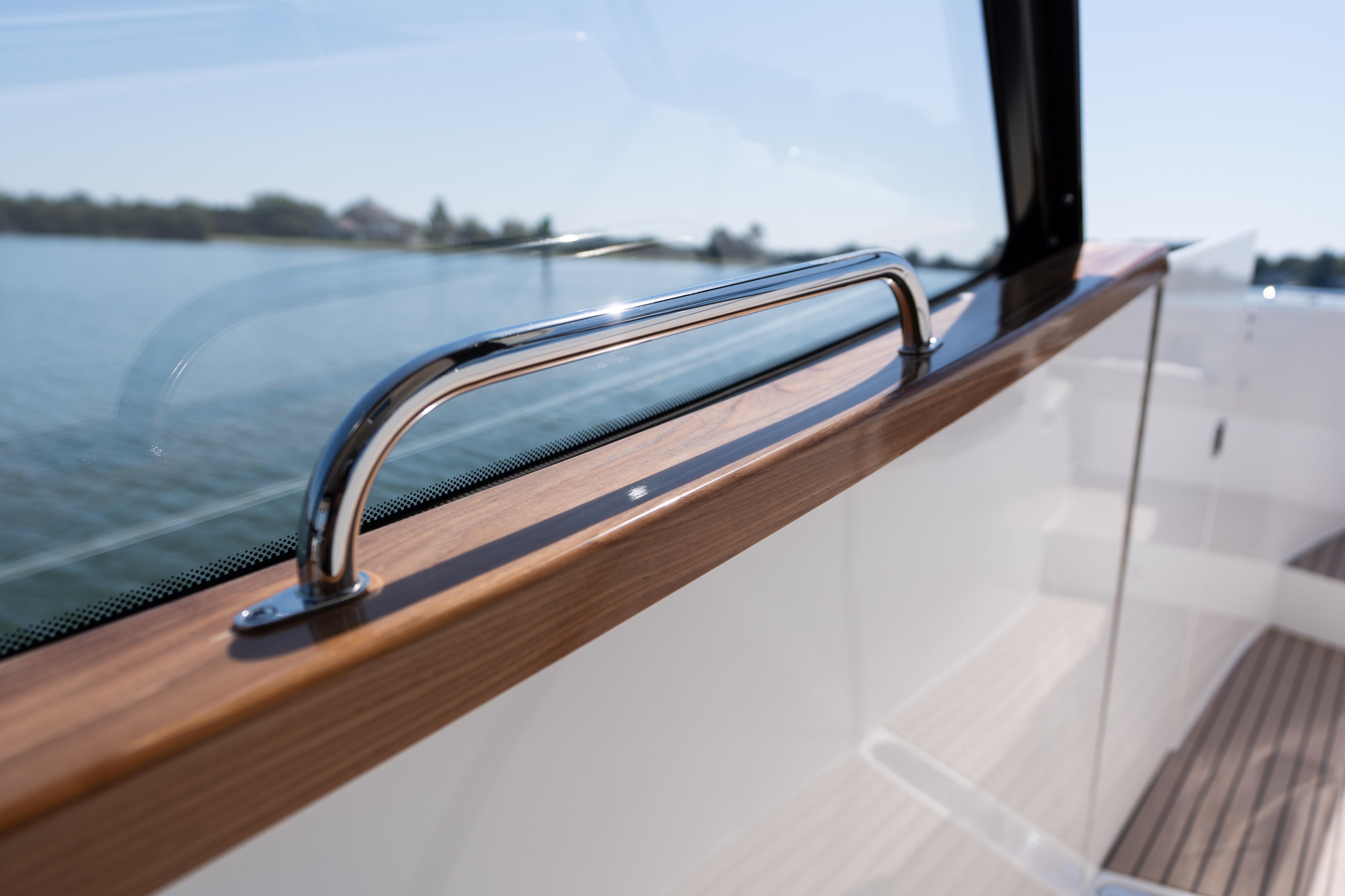 2023 MJM Yachts 4, sleek chrome railing, wooden trim, scenic water view.