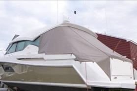 2014 Tiara 5000 Coupe yacht covered, docked near a red building.
