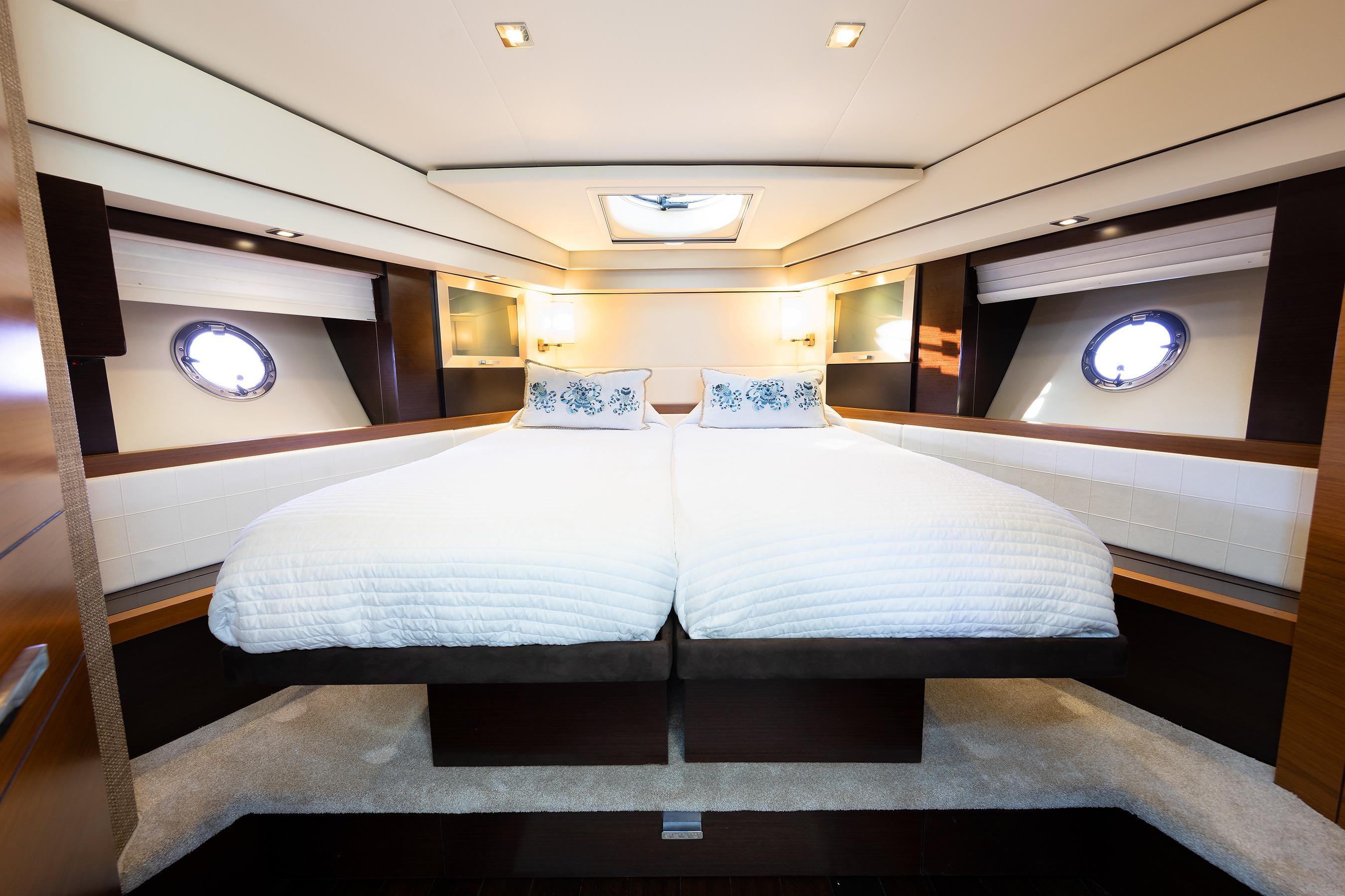 Luxurious bedroom interior of 2014 Tiara 5000 Coupe yacht with twin beds and portholes.