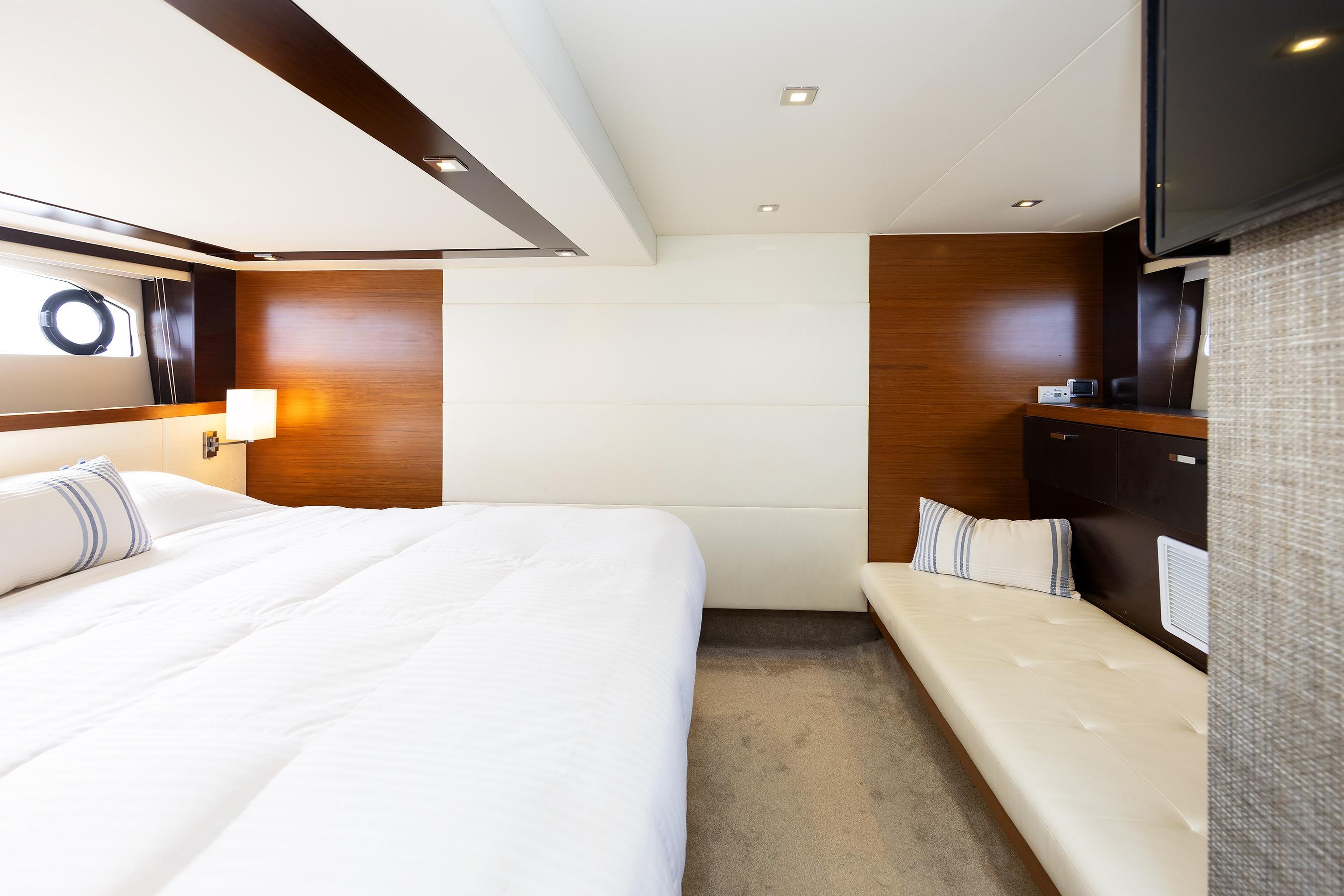 Luxurious interior of 2014 Tiara 5000 Coupe yacht with elegant wood paneling and plush bedding.