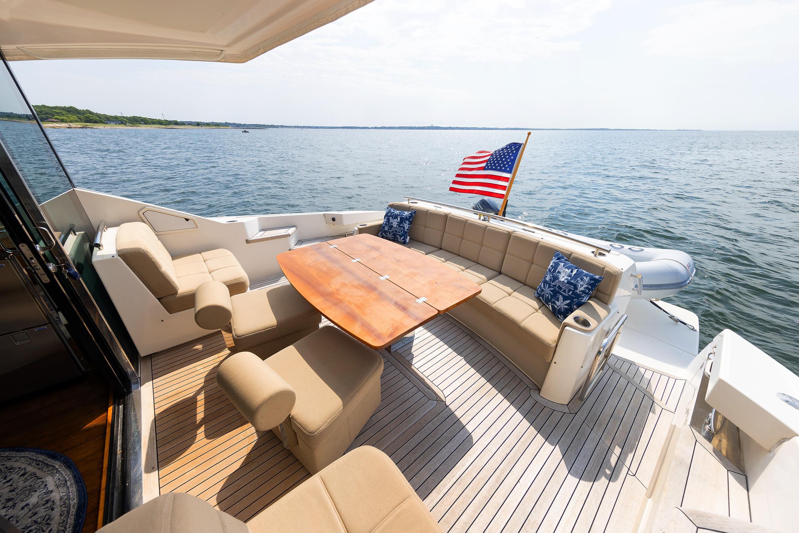 Luxurious 2014 Tiara 5000 Coupe yacht deck with seating, table, and American flag.
