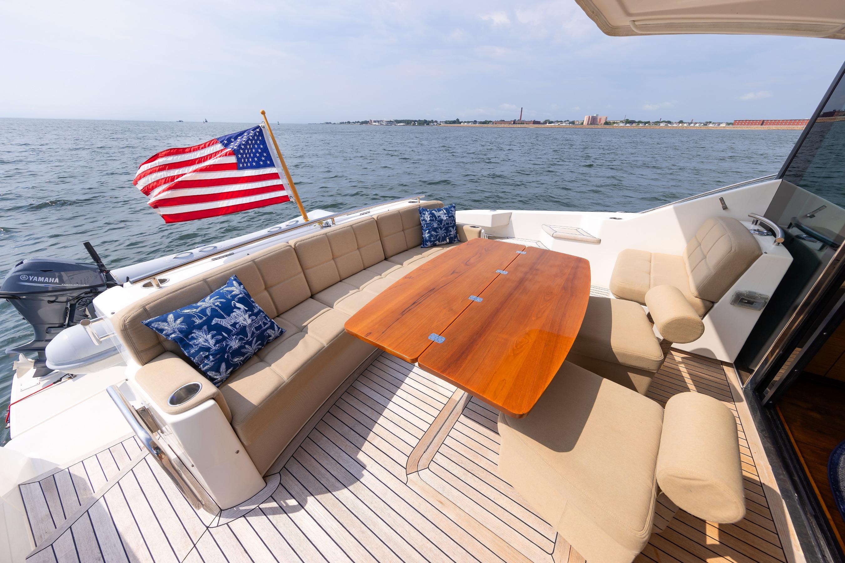 Luxurious 2014 Tiara 5000 Coupe yacht deck with seating, table, and American flag.