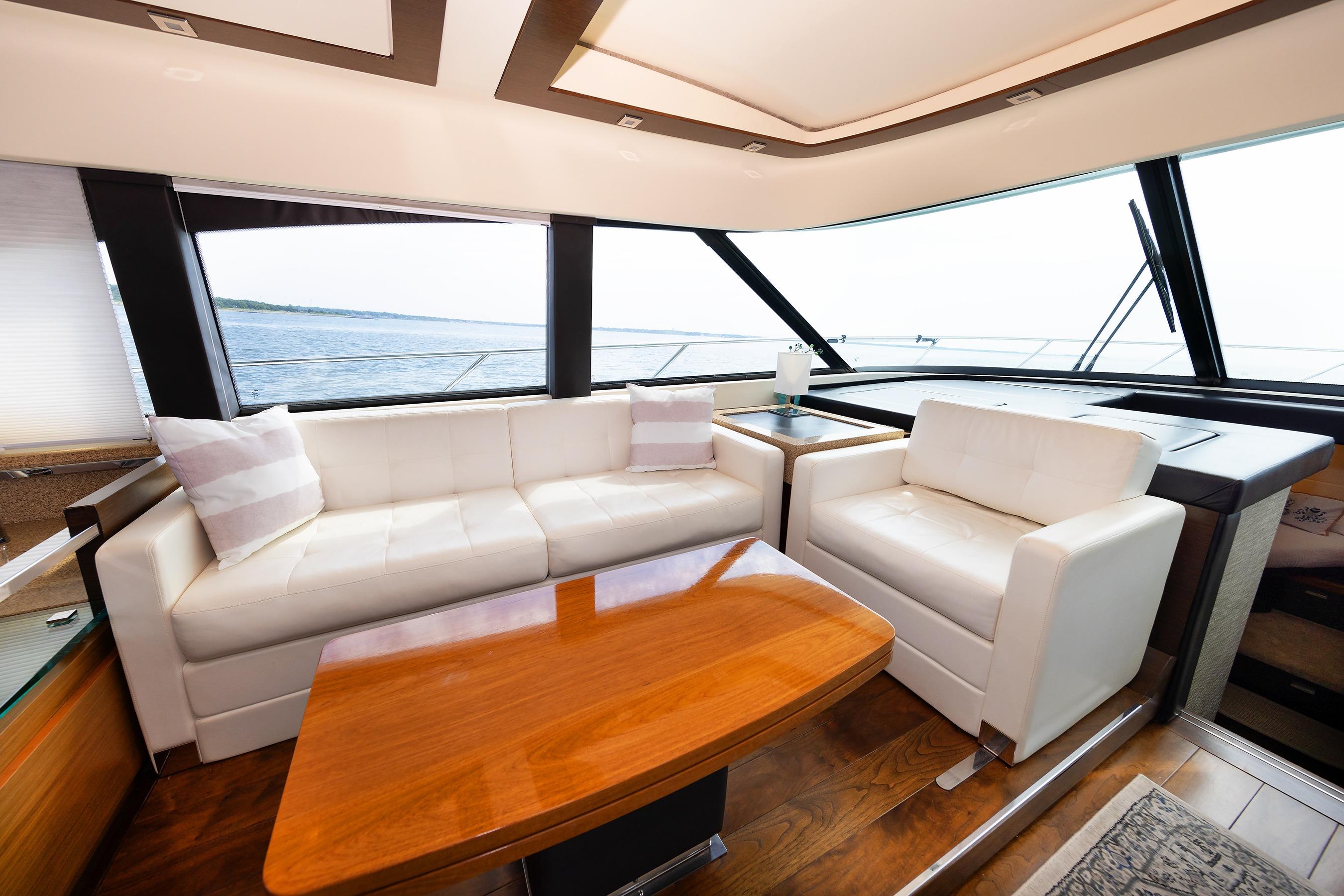 Luxurious interior of 2014 Tiara 5000 Coupe yacht with white seating and wooden table.