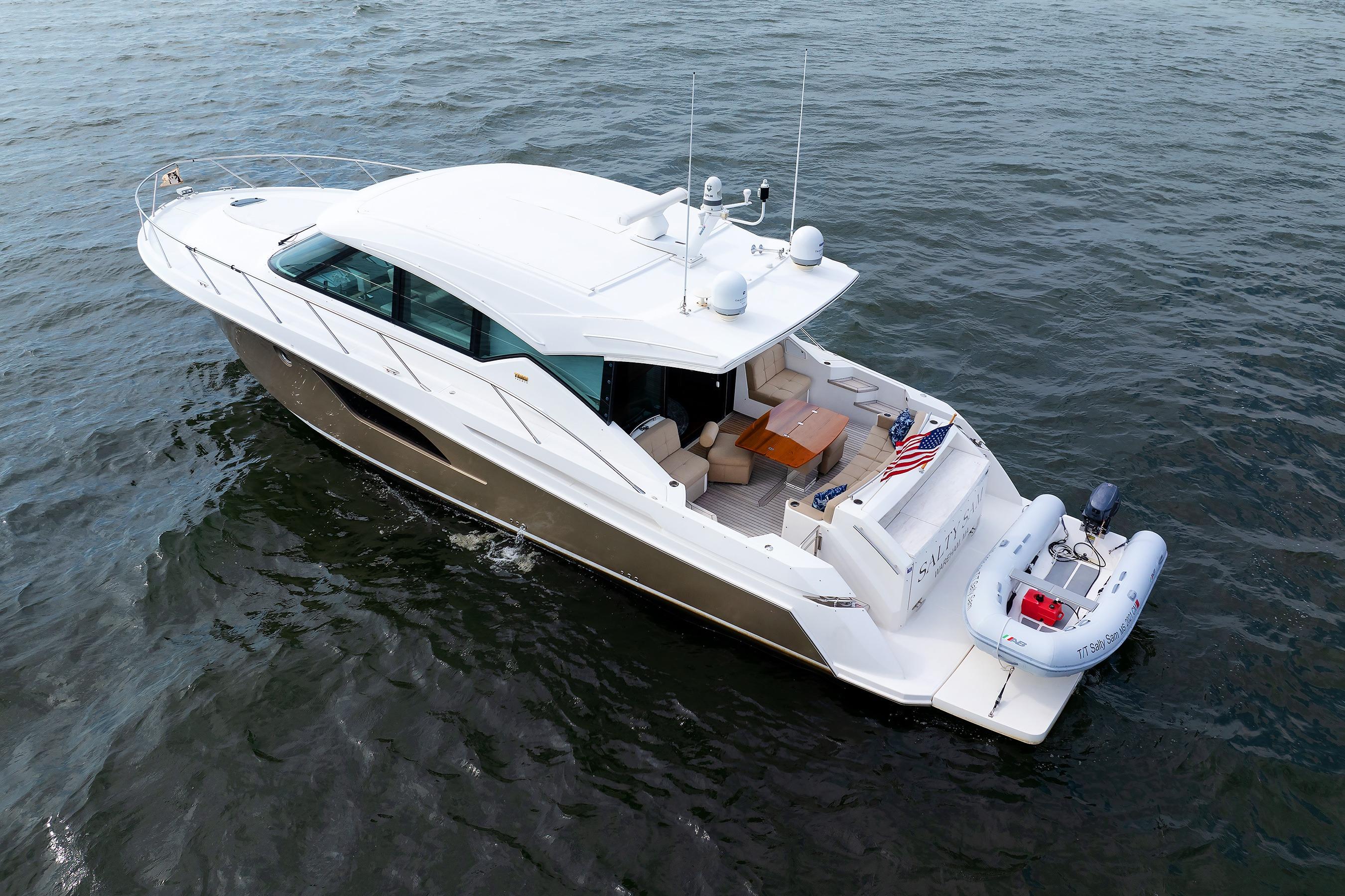 2014 Tiara 5000 Coupe yacht cruising on open water with inflatable boat attached.