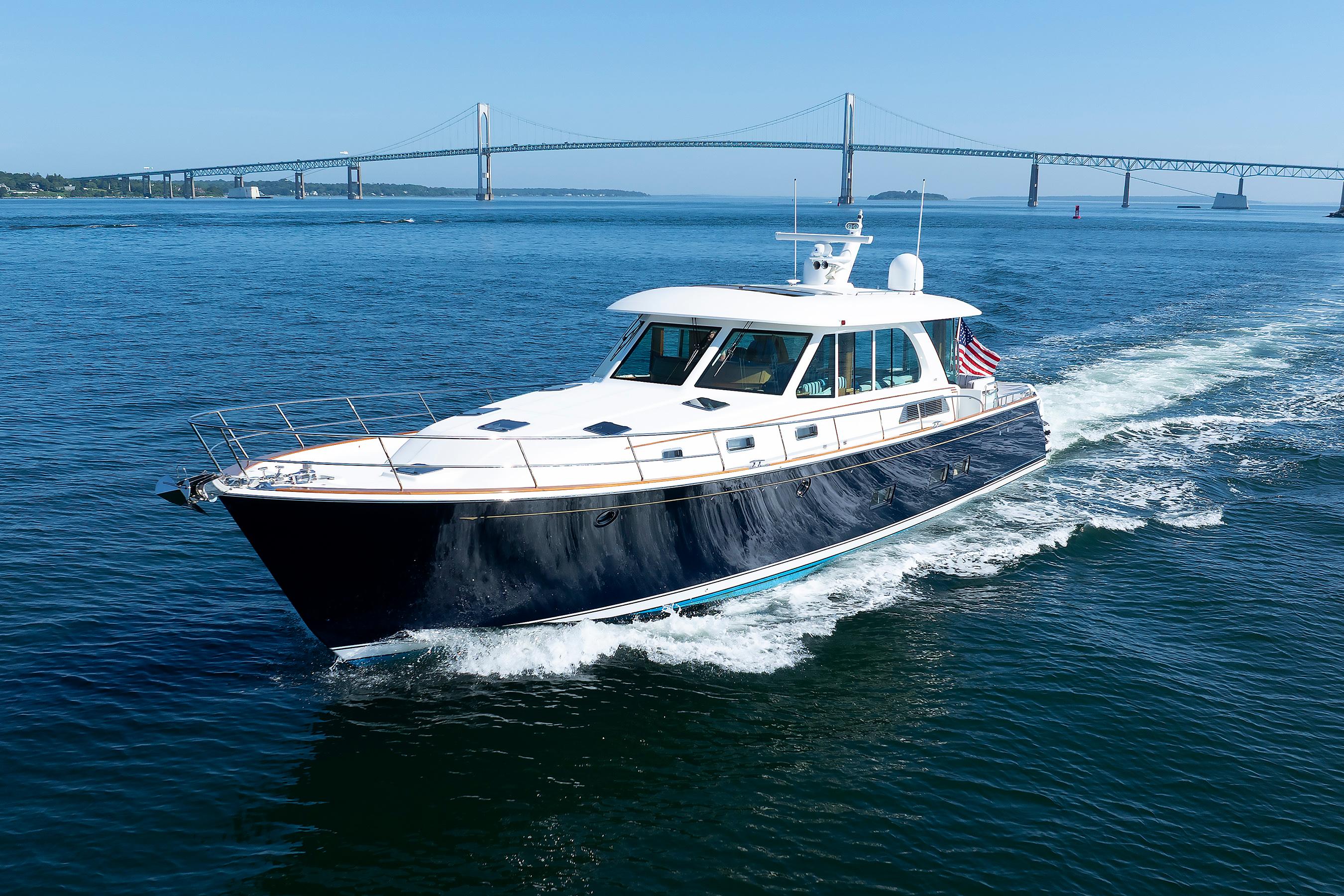 2020 Sabre 66 Dirigo Salon Express yacht cruising near a bridge on a sunny day.