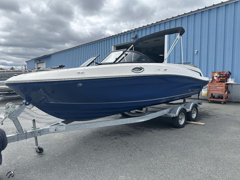 2023 Bayliner VR6 boat on trailer, parked outside blue warehouse.