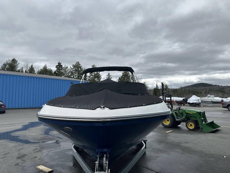 2023 Bayliner VR6 boat on trailer, covered, parked outdoors under cloudy sky.
