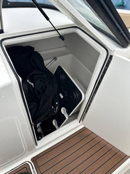 2023 Bayliner VR6 boat storage compartment with gear inside, featuring sleek white design and wood-textured flooring.