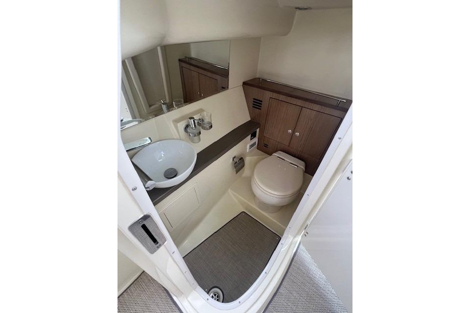 2021 Chris-Craft Launch 35 GT boat bathroom with sink, toilet, and wooden cabinetry.
