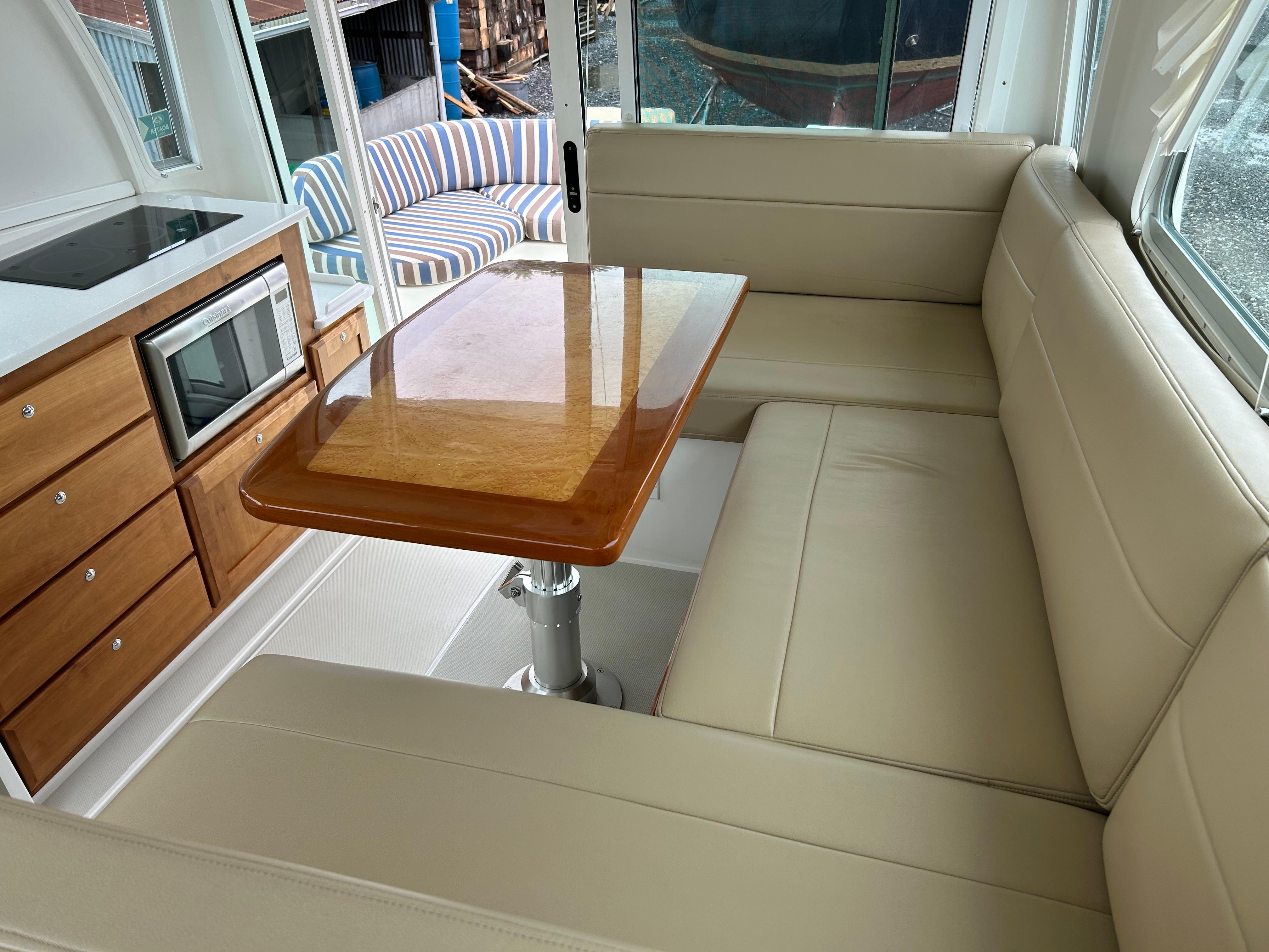 2018 Back Cove 32 interior with beige seating, wooden table, and kitchenette.