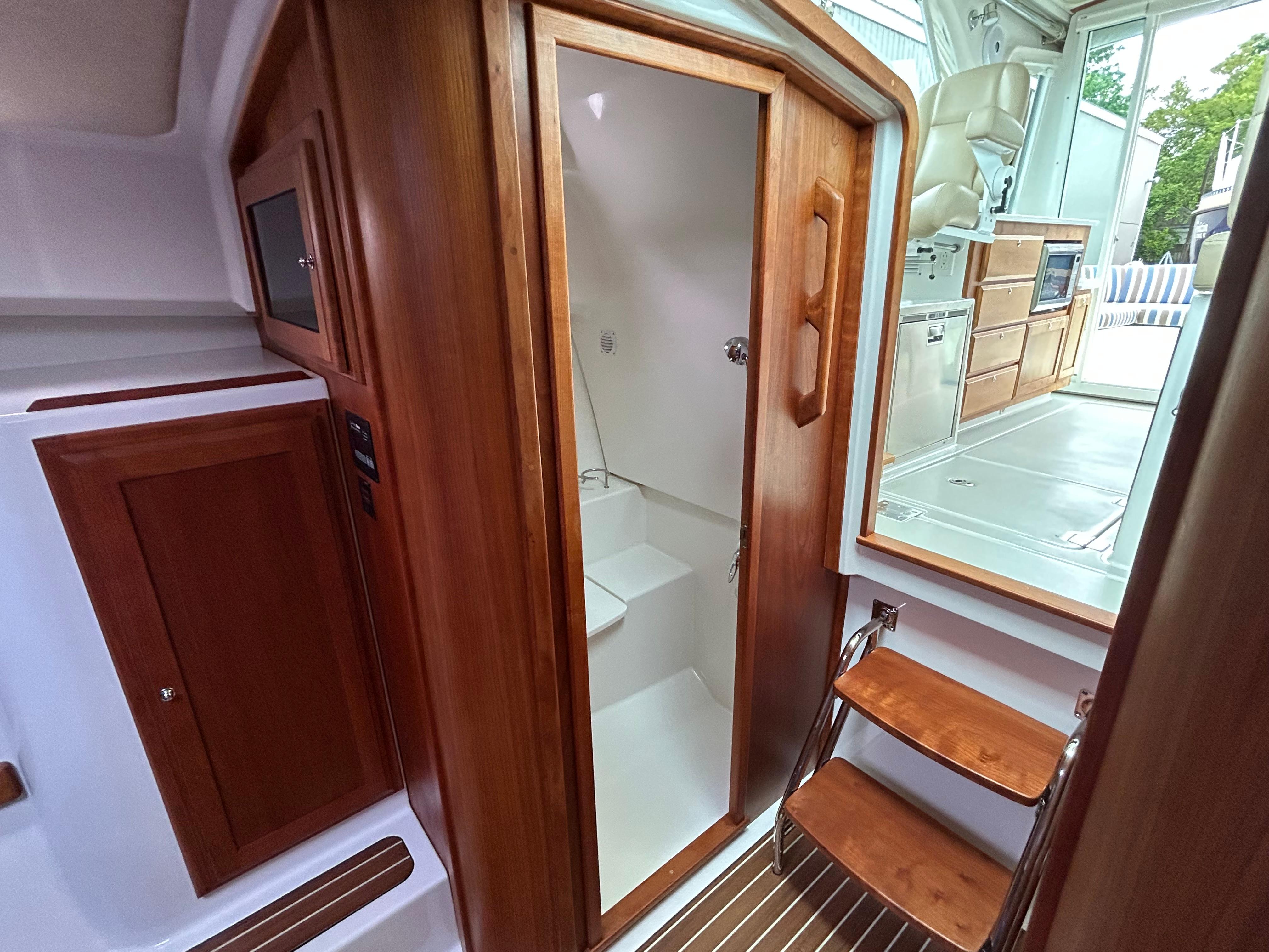 Interior of 2018 Back Cove 32 boat, featuring wooden cabinetry and compact bathroom.