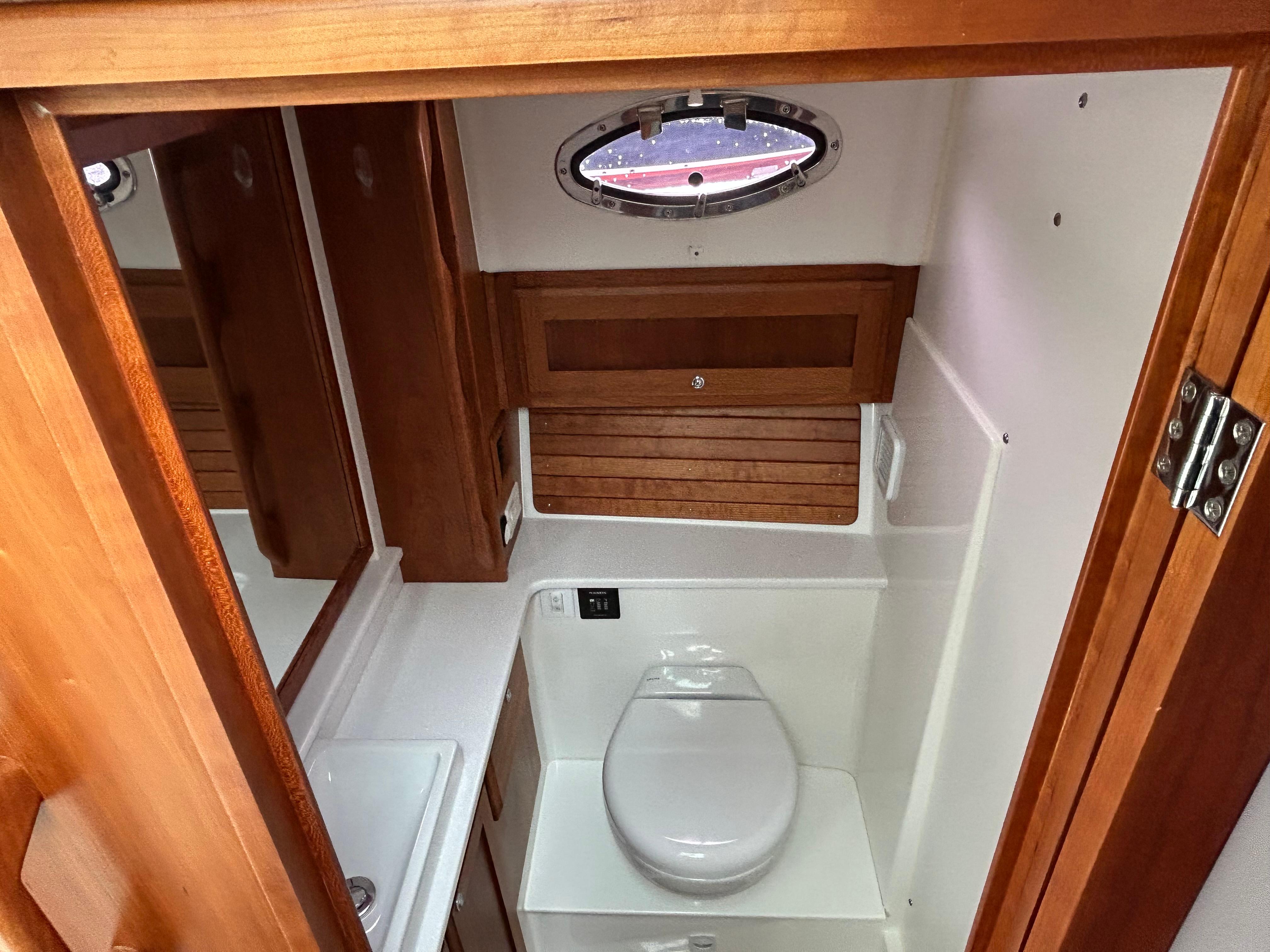 2018 Back Cove 32 yacht bathroom with wooden accents and porthole window.