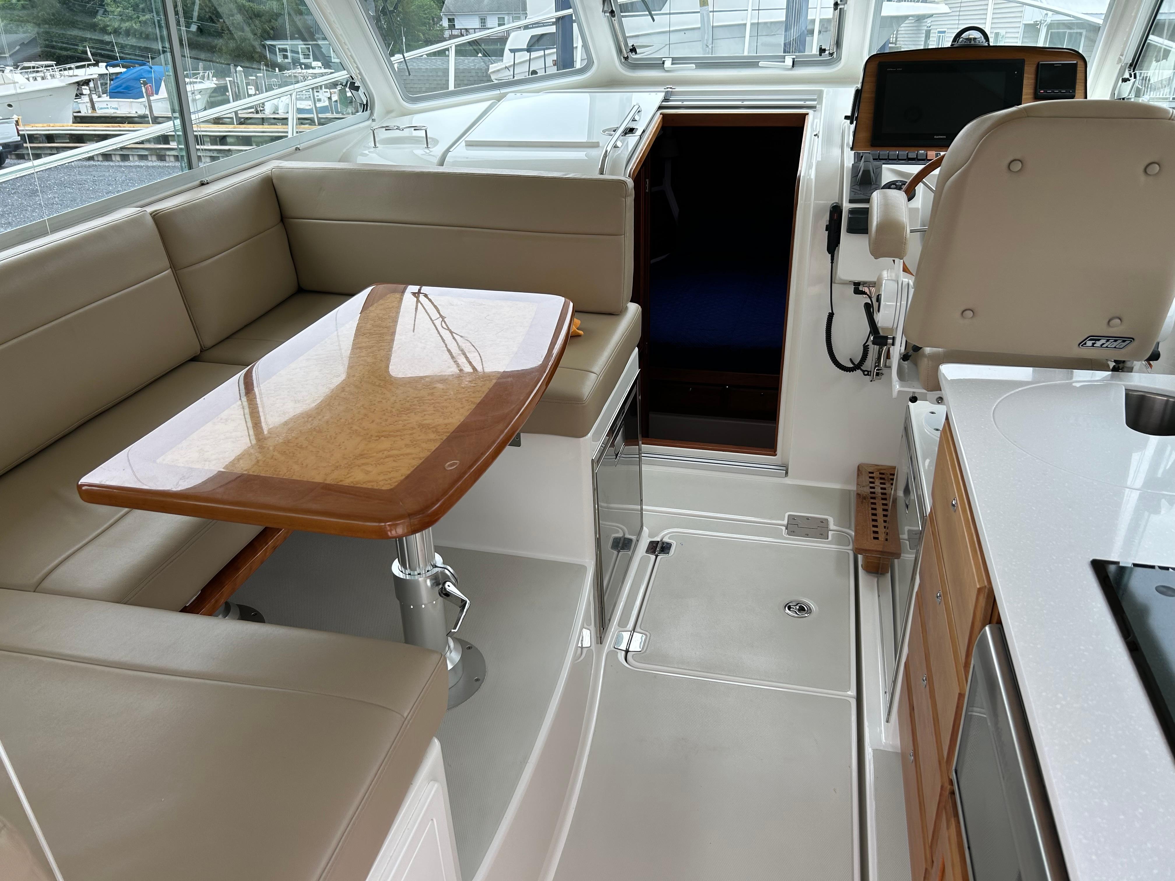 2018 Back Cove 32 yacht interior with beige seating, wooden table, and navigation area.