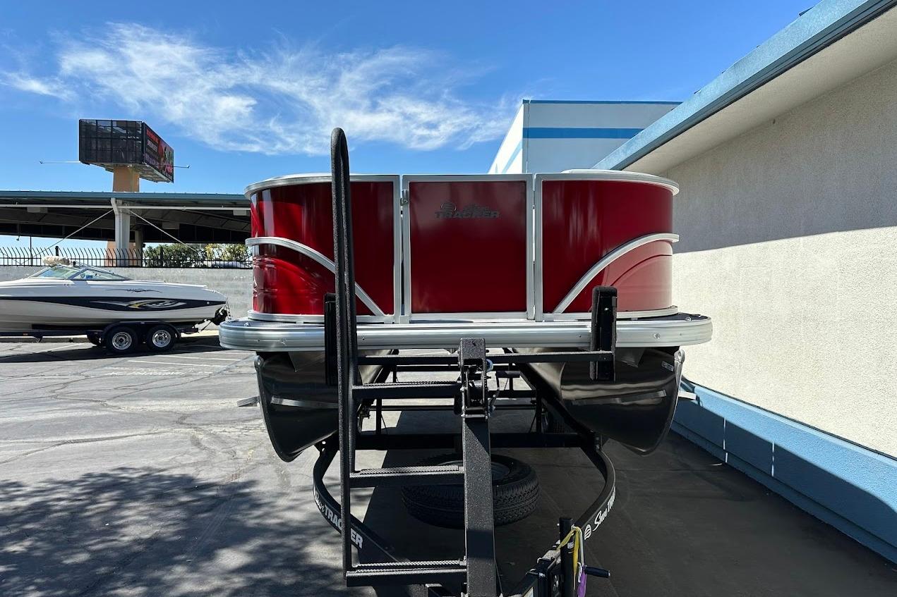 2026 Sun Tracker Party Barge 18 DLX pontoon boat on trailer, red exterior, sunny day.
