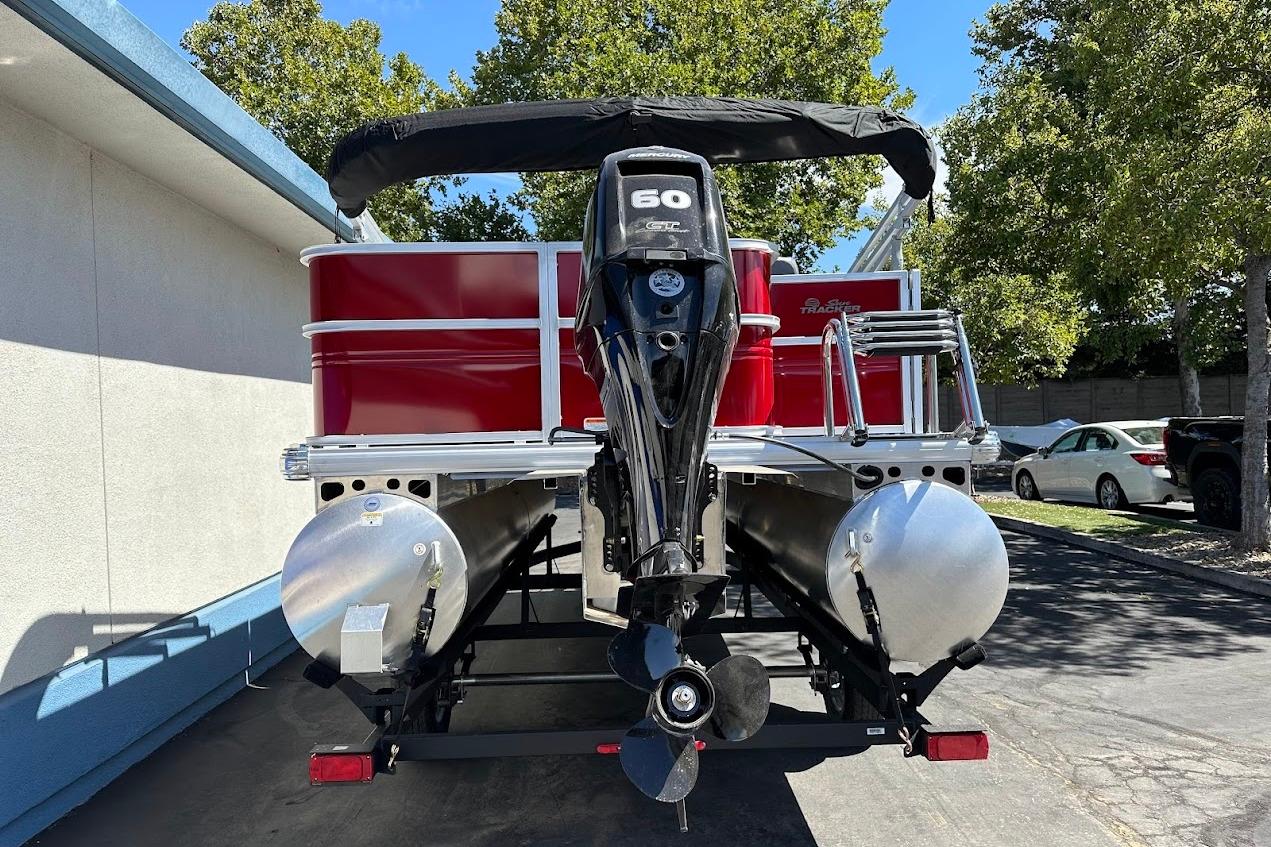 2026 Sun Tracker Party Barge 18 DLX pontoon boat with 60 HP engine, parked outdoors.