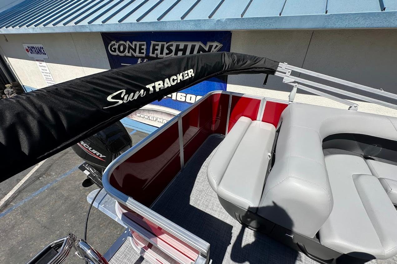 2026 Sun Tracker Party Barge 18 DLX with seating and canopy, parked near a 