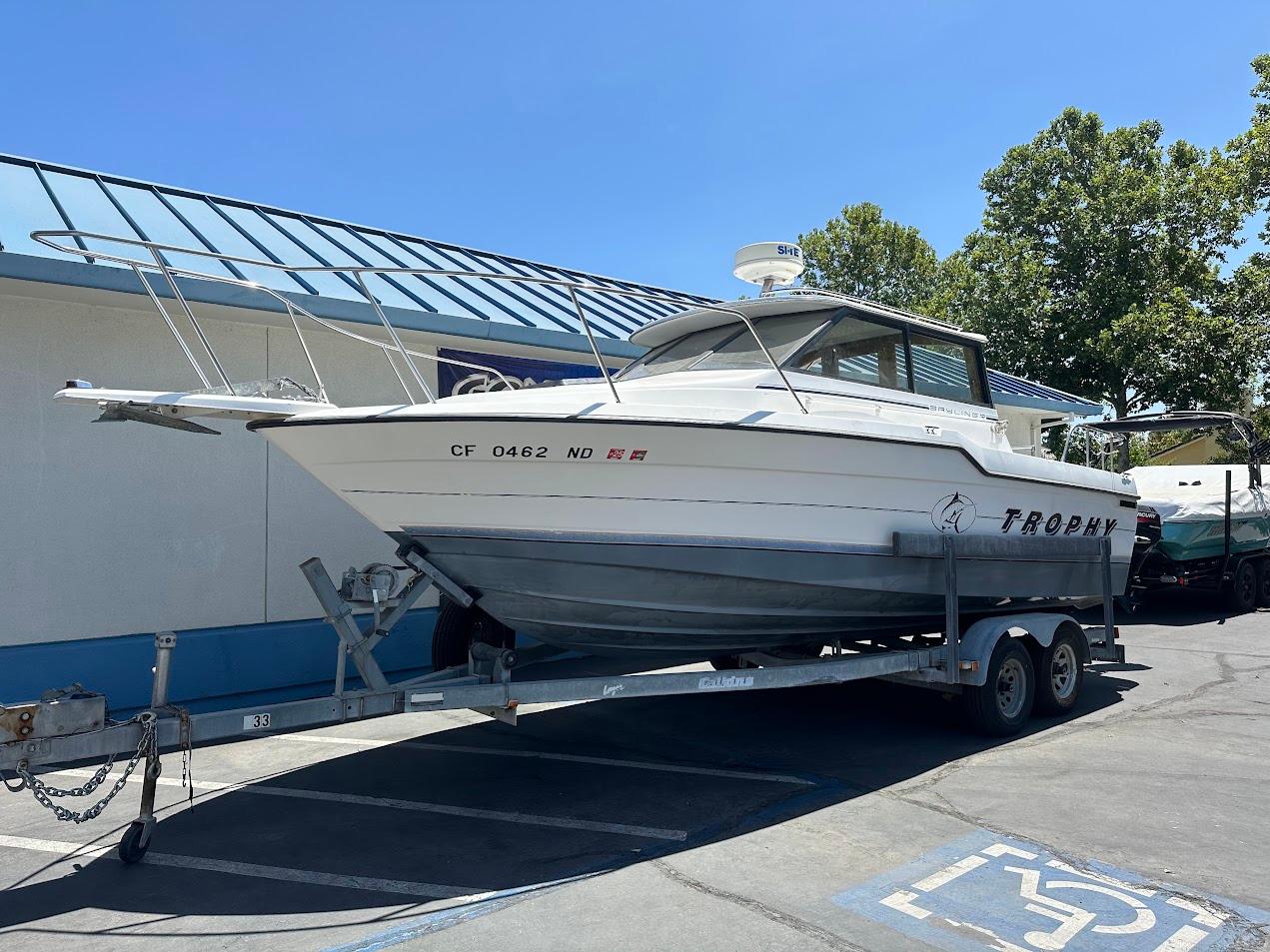 1992 Bayliner 2359 Trophy boat on trailer, parked outdoors under clear blue sky.