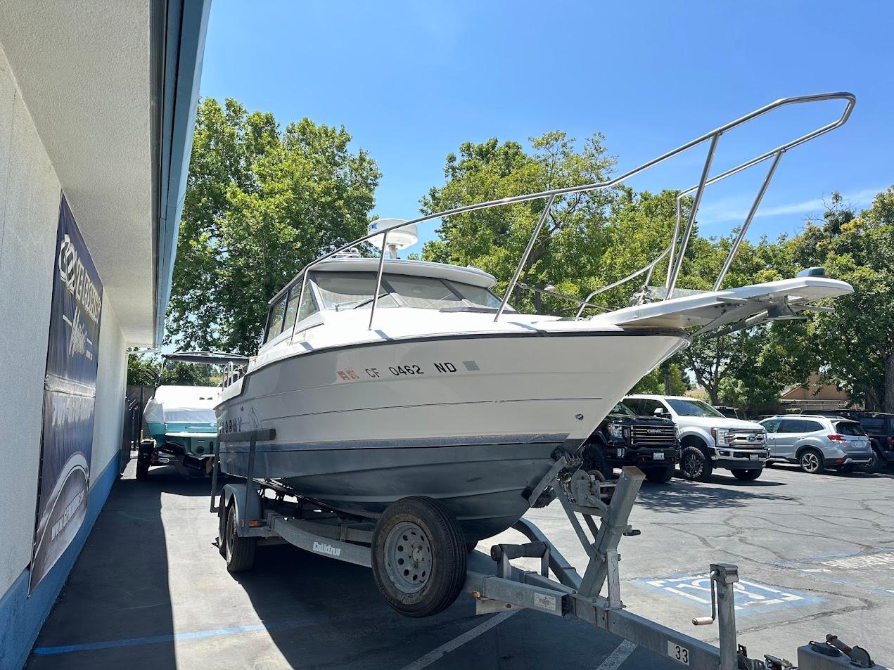 1992 Bayliner 2359 Trophy boat on trailer in parking lot, sunny day.