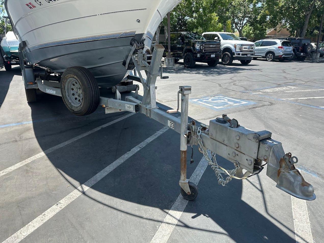 1992 Bayliner 2359 Trophy boat on trailer in parking lot, sunny day.
