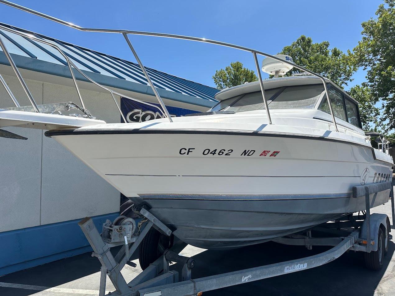 1992 Bayliner 2359 Trophy boat on trailer, parked outdoors under clear blue sky.