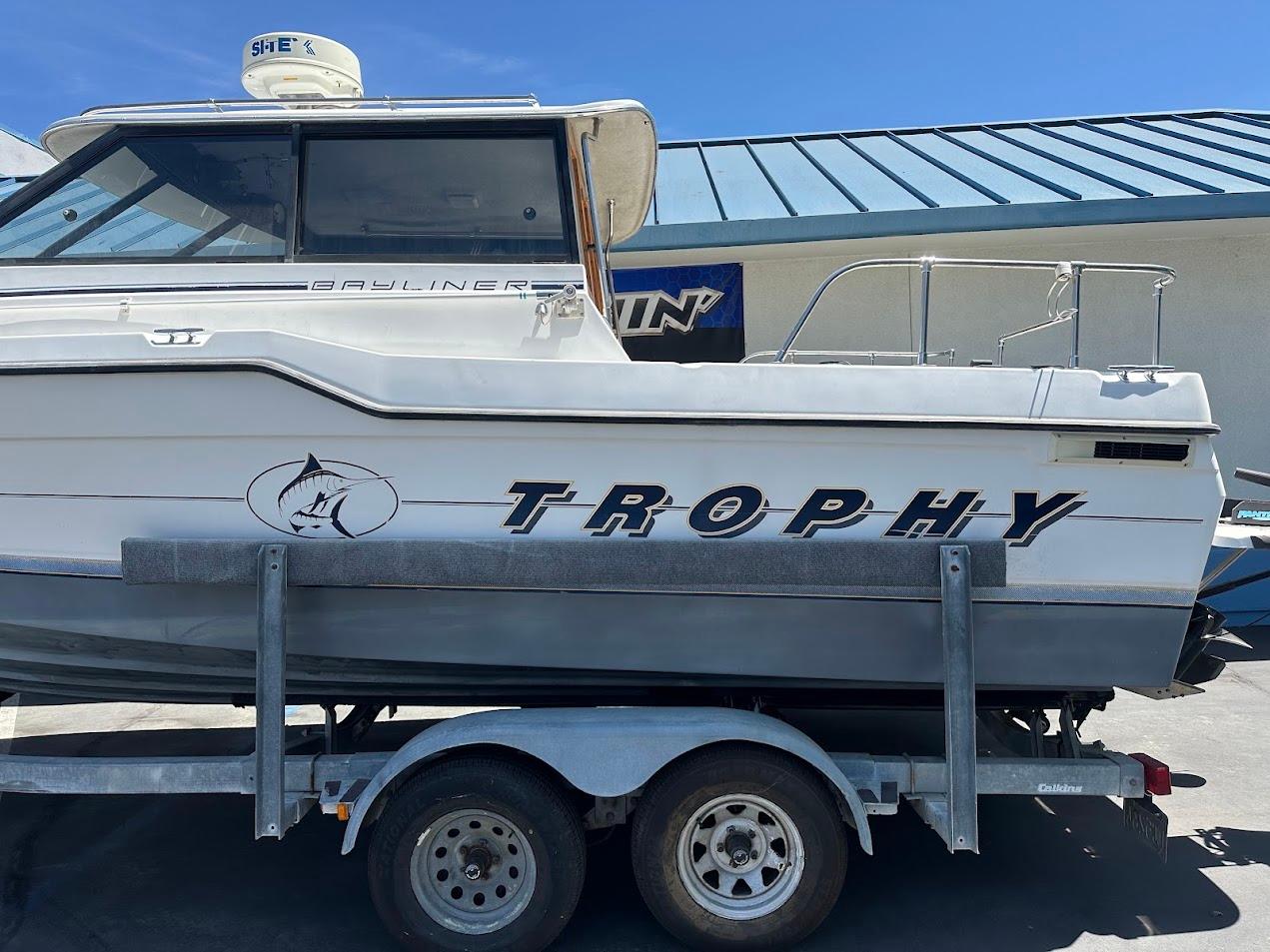 1992 Bayliner 2359 Trophy boat on trailer, side view, with clear blue sky background.