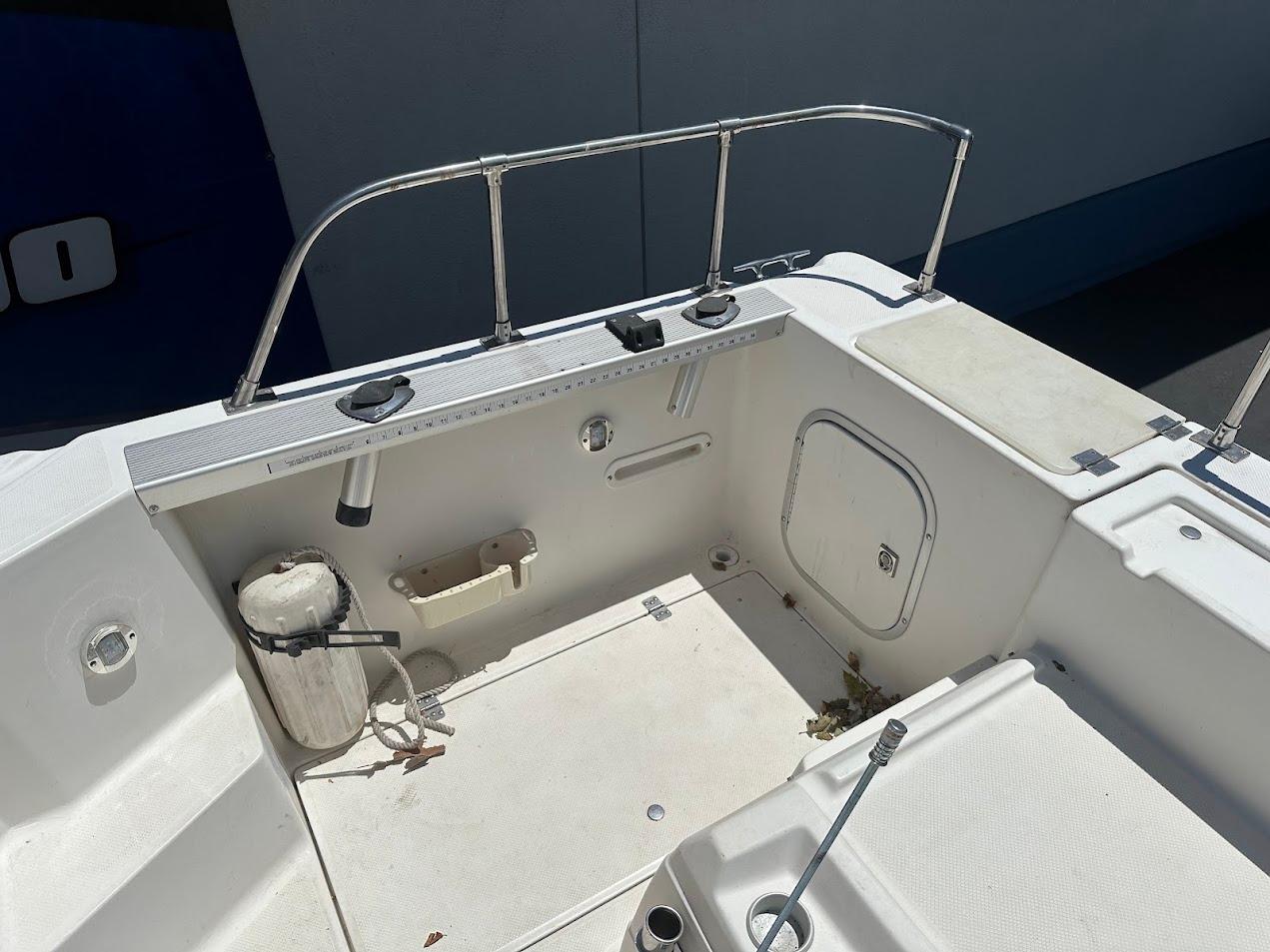 1992 Bayliner 2359 Trophy boat deck with railing, storage hatch, and fishing rod holder.