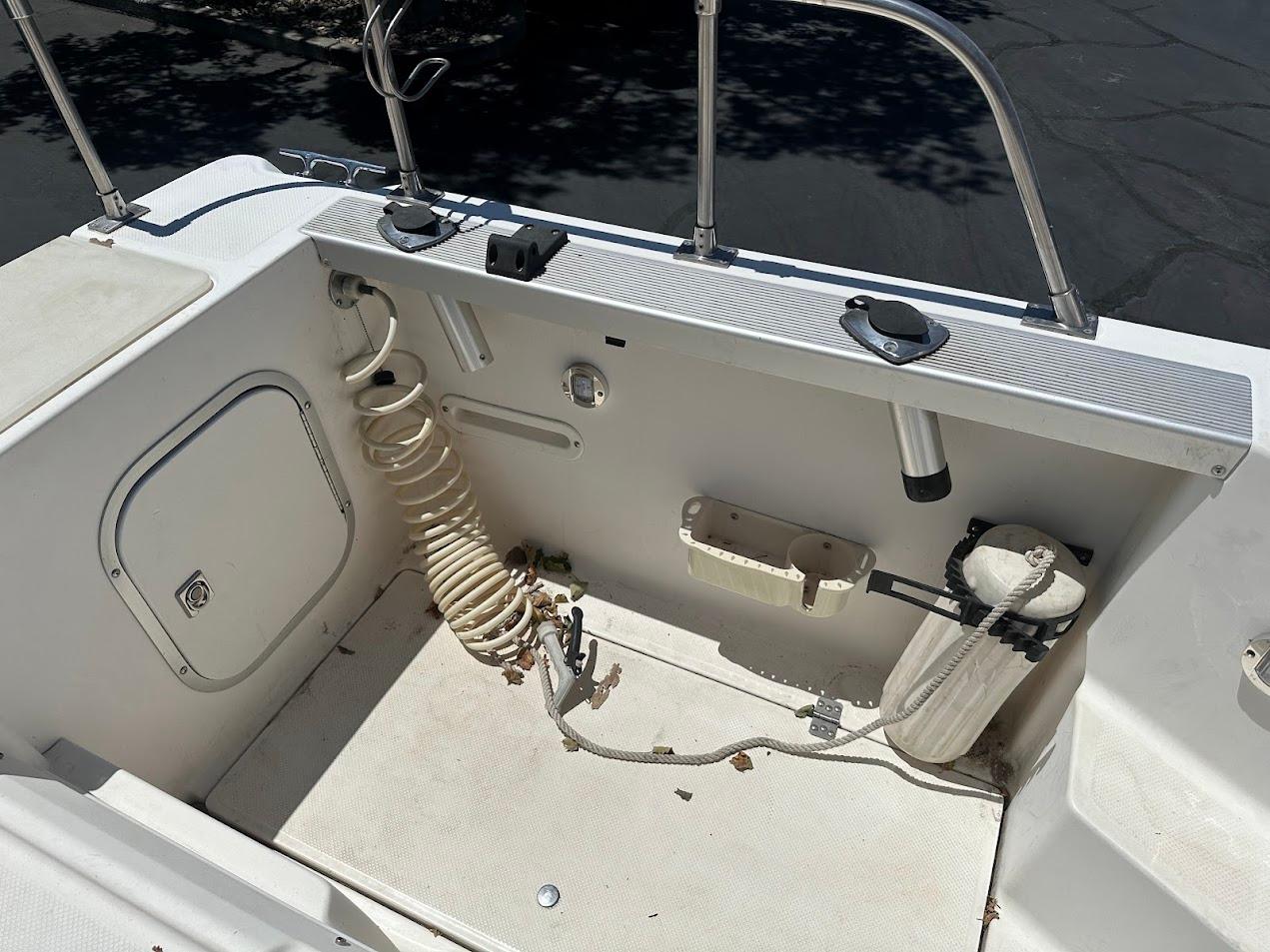 1992 Bayliner 2359 Trophy boat deck with coiled hose and storage compartments.