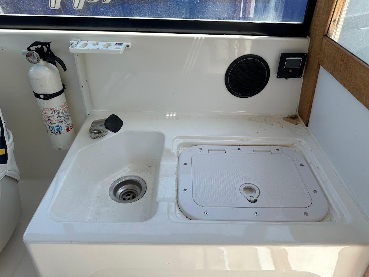 Interior of 1992 Bayliner 2359 Trophy boat with sink, fire extinguisher, and storage compartment.