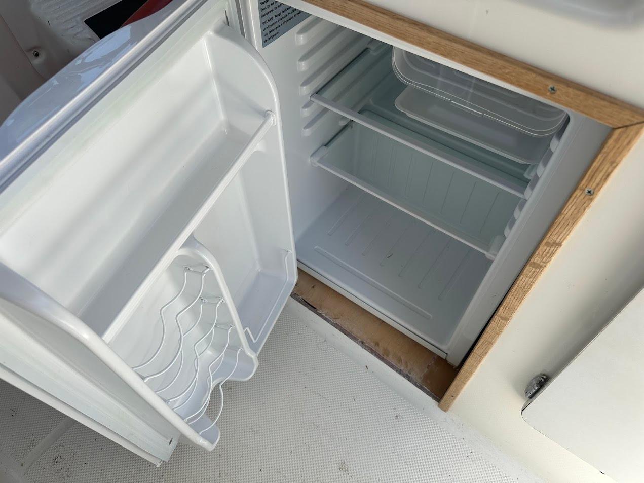 Open fridge inside 1992 Bayliner 2359 Trophy boat, showing empty shelves and door storage.