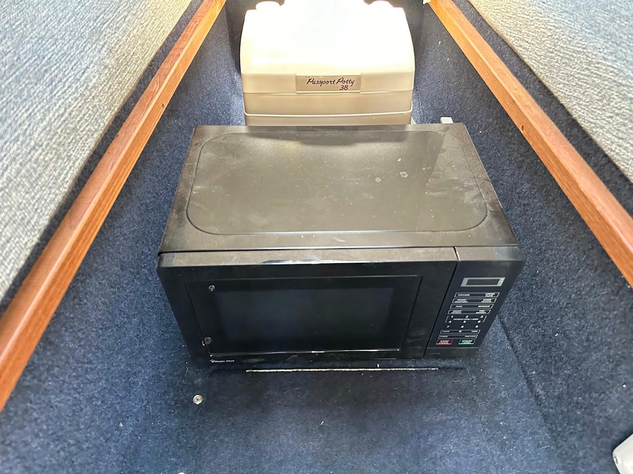 Microwave and portable toilet inside 1992 Bayliner 2359 Trophy boat cabin.