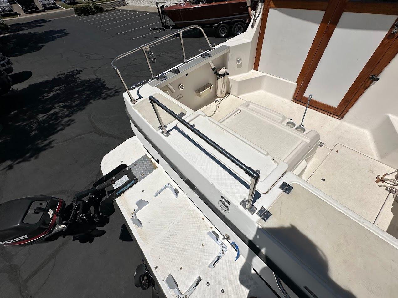 1992 Bayliner 2359 Trophy boat deck with Mercury outboard motor, parked in a lot.