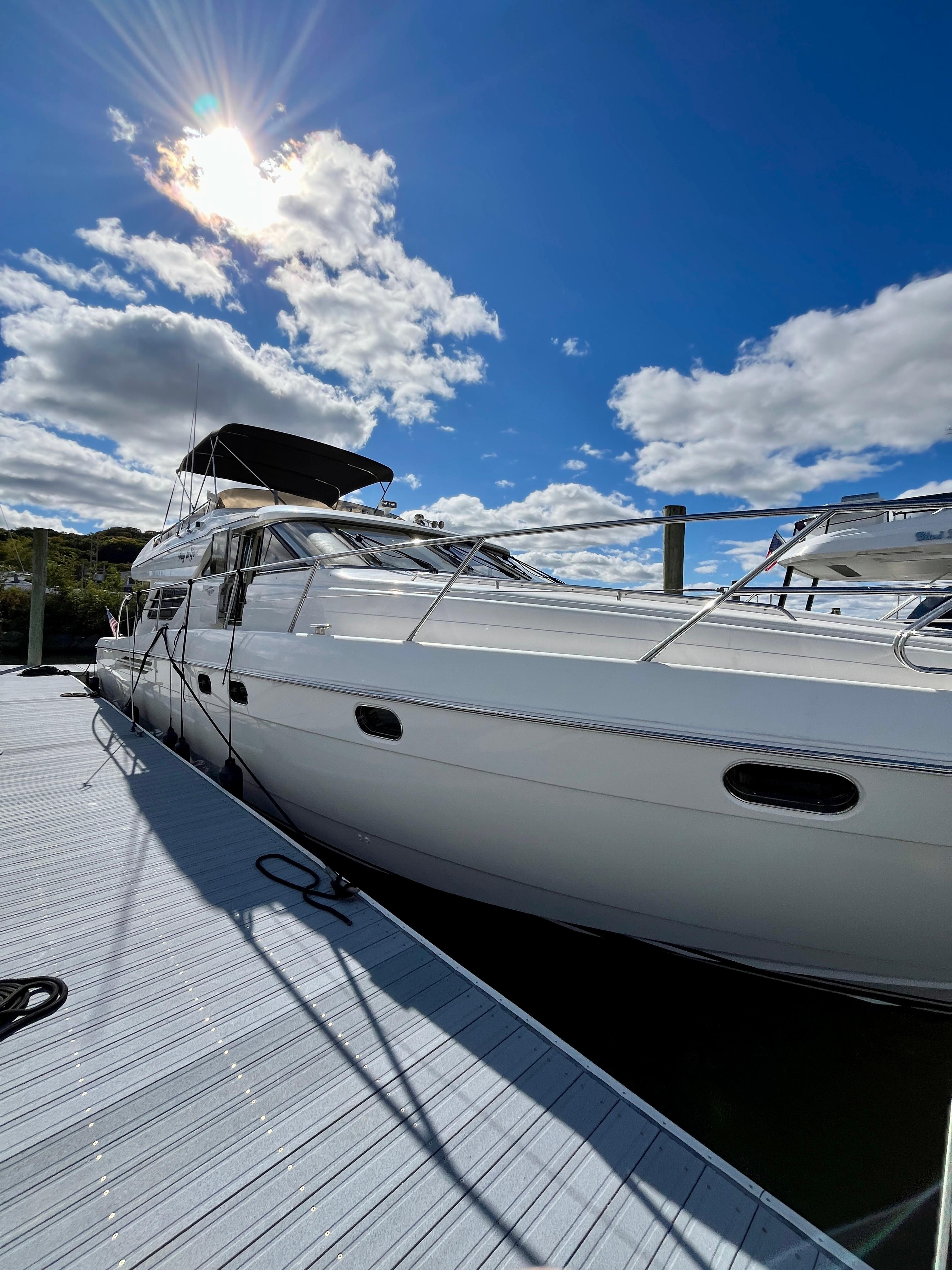 1999 Viking Sport Cruisers 60 Flybridge yacht docked under a bright blue sky.