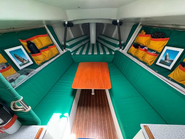 Interior of 2000 Wyliecat 48 sailboat with green seating and wooden table.