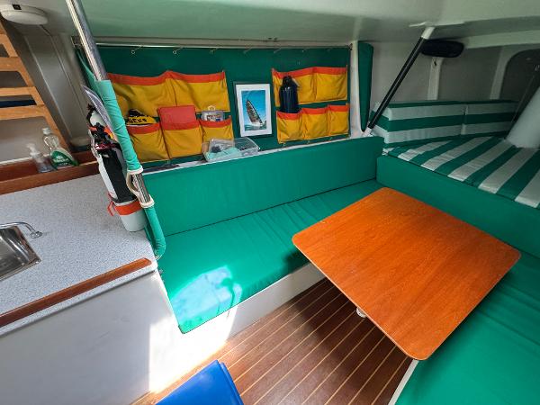 Interior of 2000 Wyliecat 48 sailboat with green seating and wooden table.
