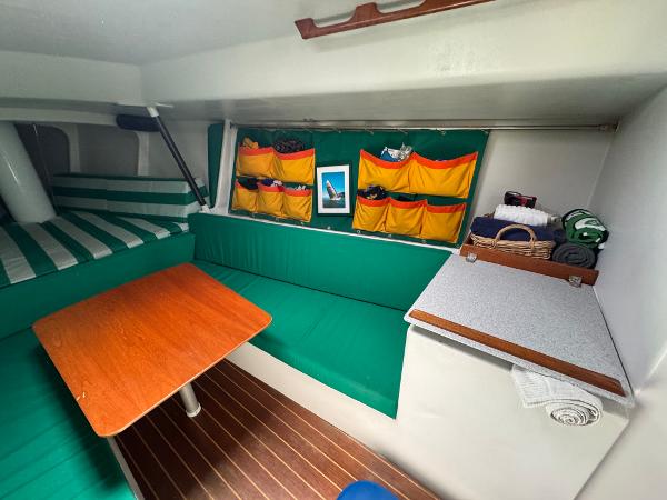 Cozy interior of 2000 Wyliecat 48 sailboat with green seating and wooden table.
