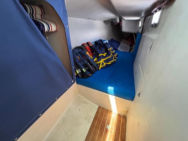 Cozy cabin interior of 2000 Wyliecat 48 sailboat with life jackets and blue bedding.