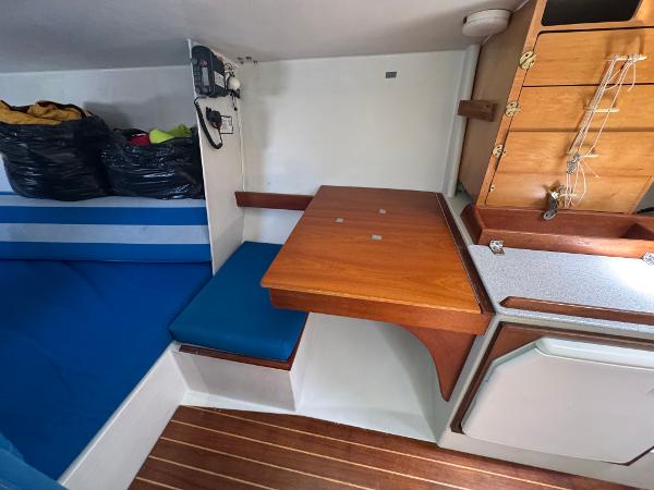 Interior of 2000 Wyliecat 48 sailboat with wooden table and blue seating.