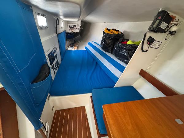 Interior of a 2000 Wyliecat 48 sailboat with blue cushions and wooden table.